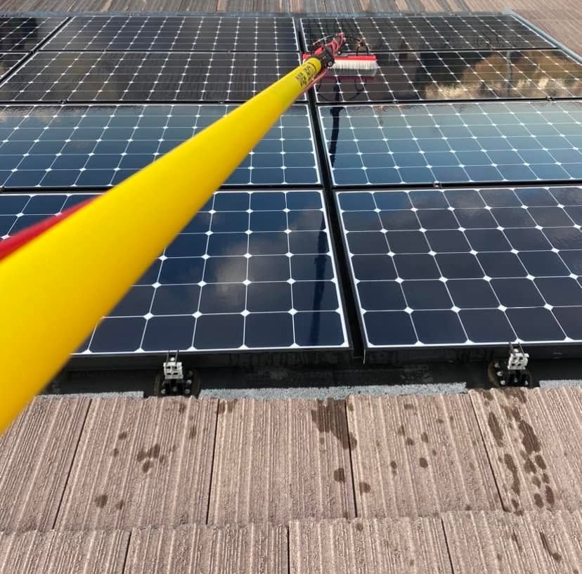 Yellow pole pointing at rooftop solar panels under bright sunlight