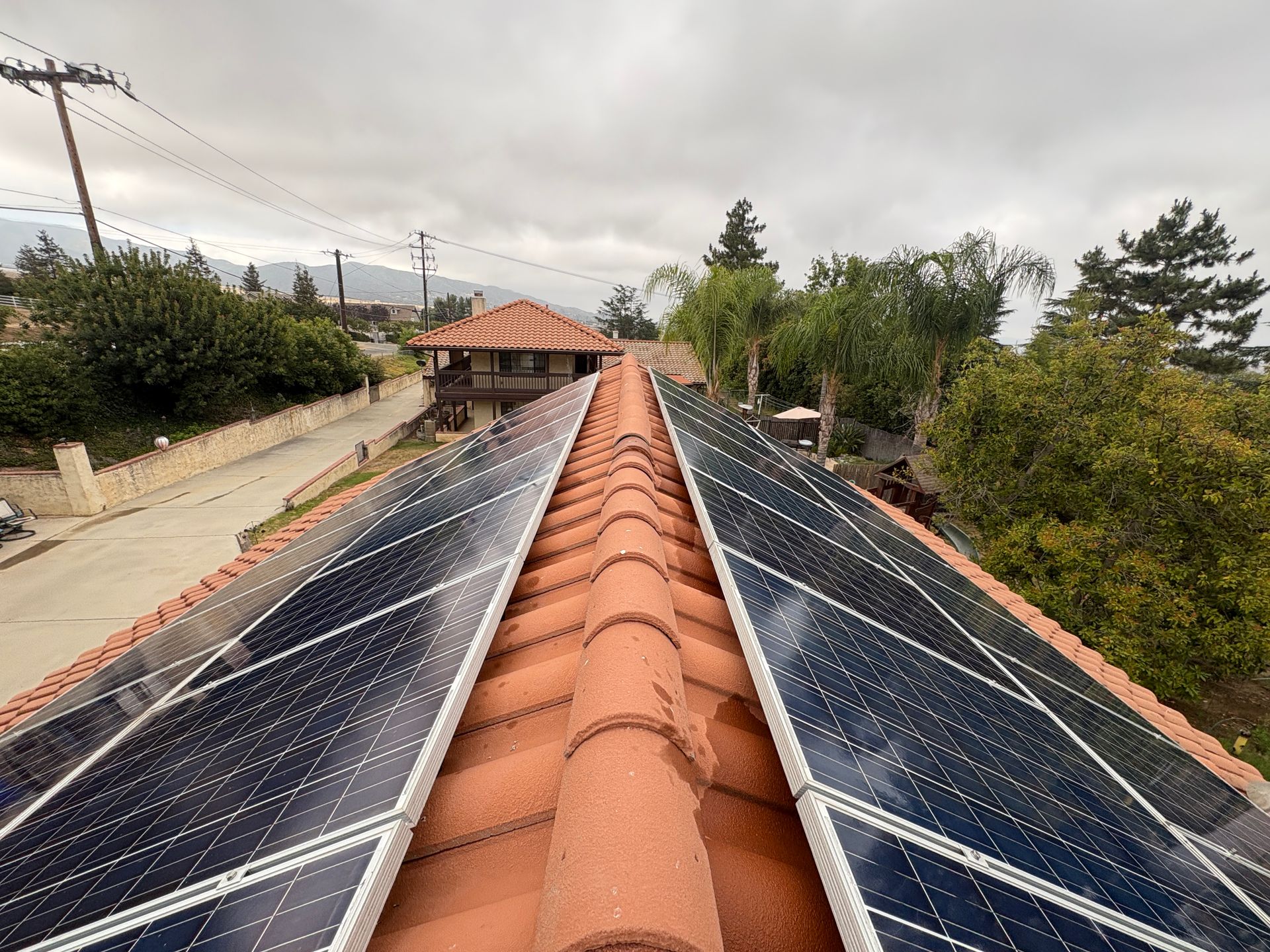 Solar panels on a terracotta rooftop in a cloudy rural setting in Yucaipa, CA