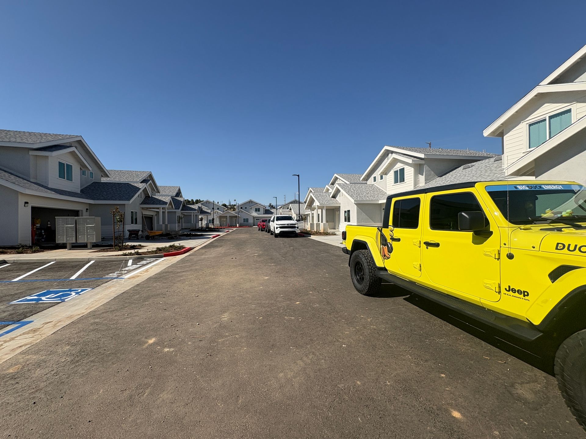 New residential street with parked cars and a bright yellow Jeep in the foreground