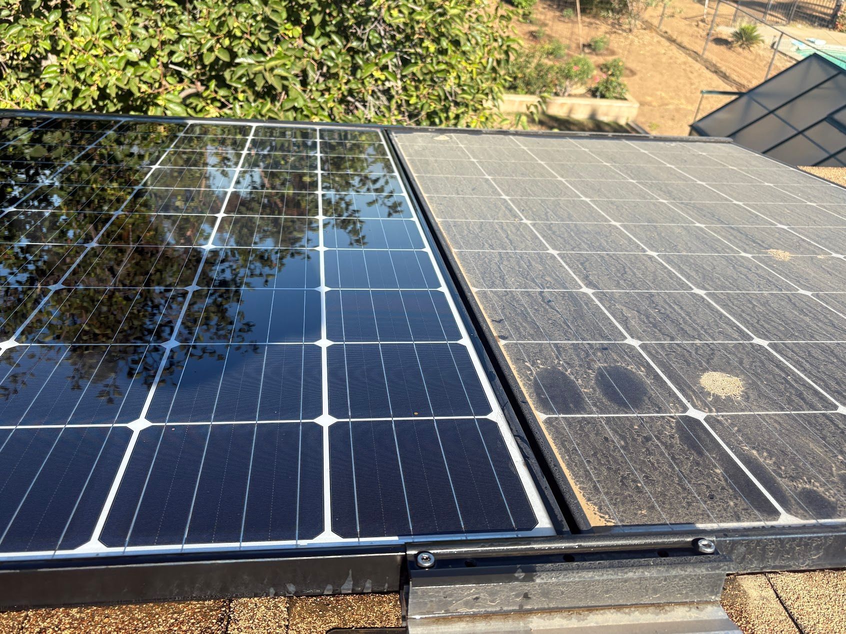 Solar panels on a rooftop, one section clean and reflective, the other dusty and worn