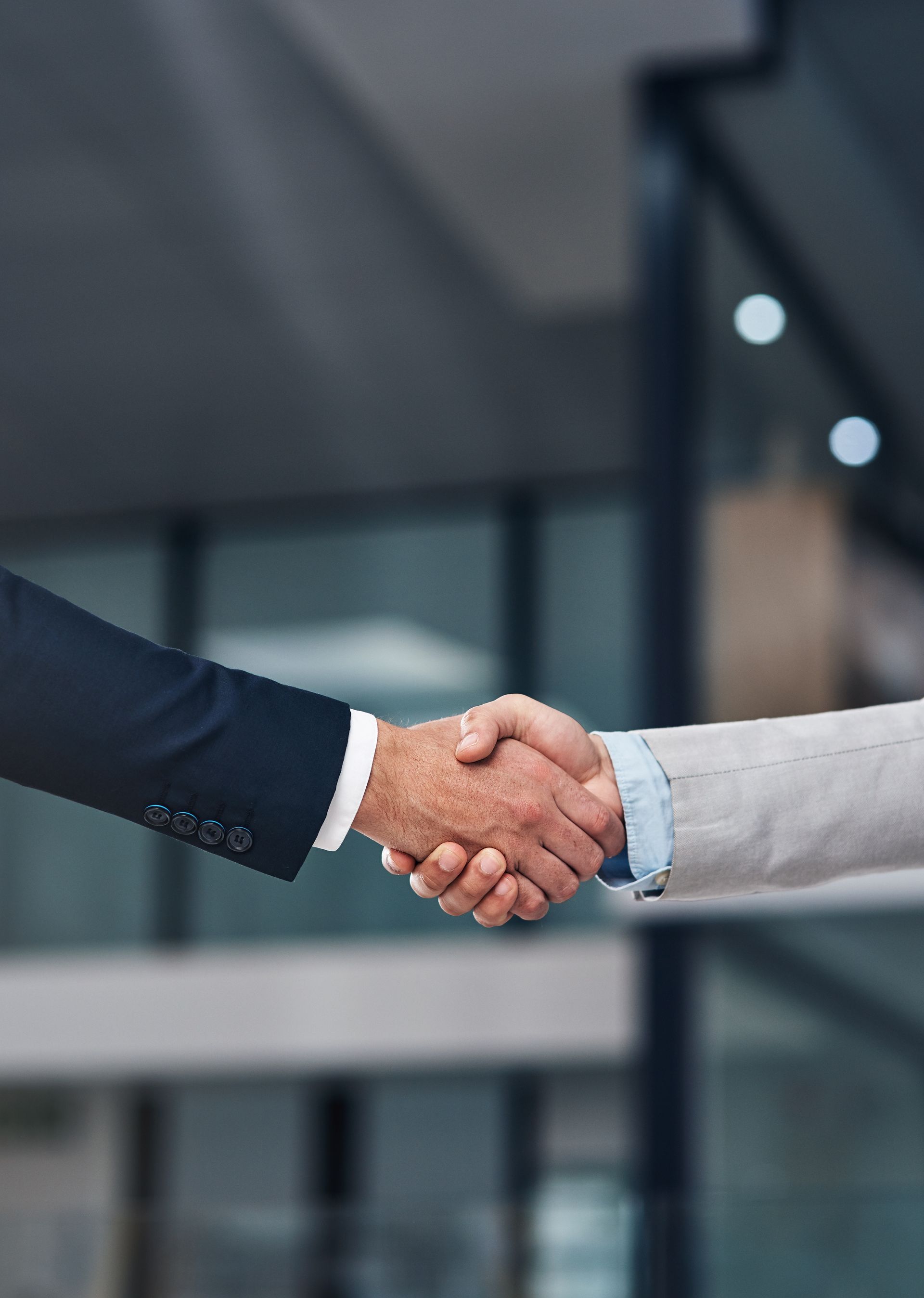 Two people in business attire shaking hands in an office setting