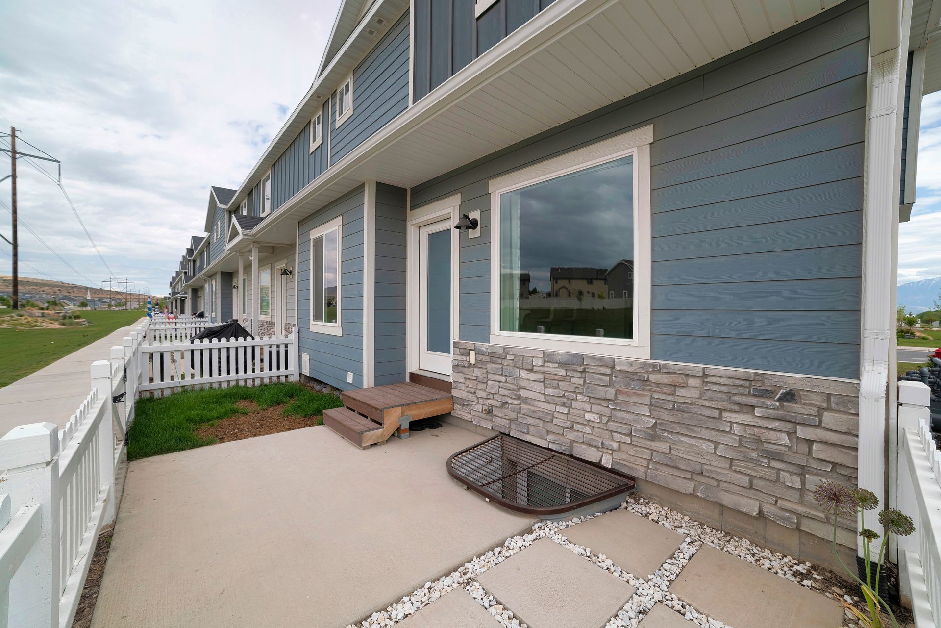 Blue townhouses with white trim and a concrete porch. Stone accents on the lower facade.