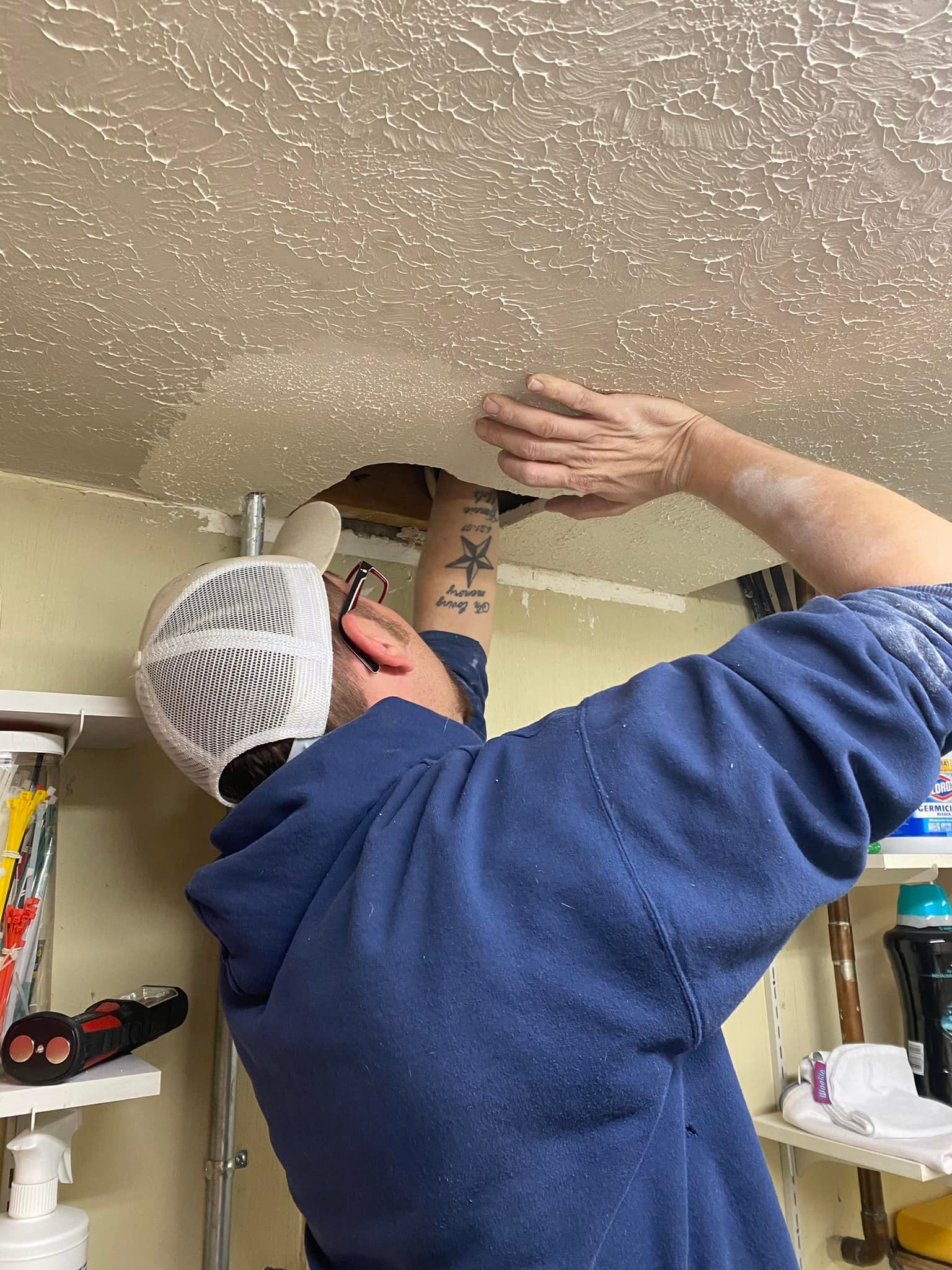 A man is fixing a hole in the ceiling.