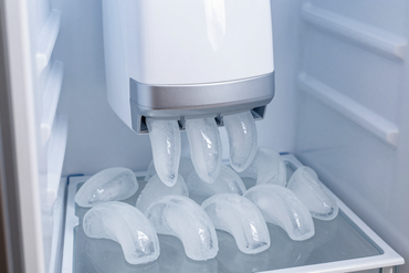 Ice maker producing crescent ice cubes in a refrigerator freezer