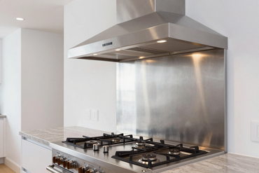 Stainless steel range hood above a gas range in an open-plan kitchen
