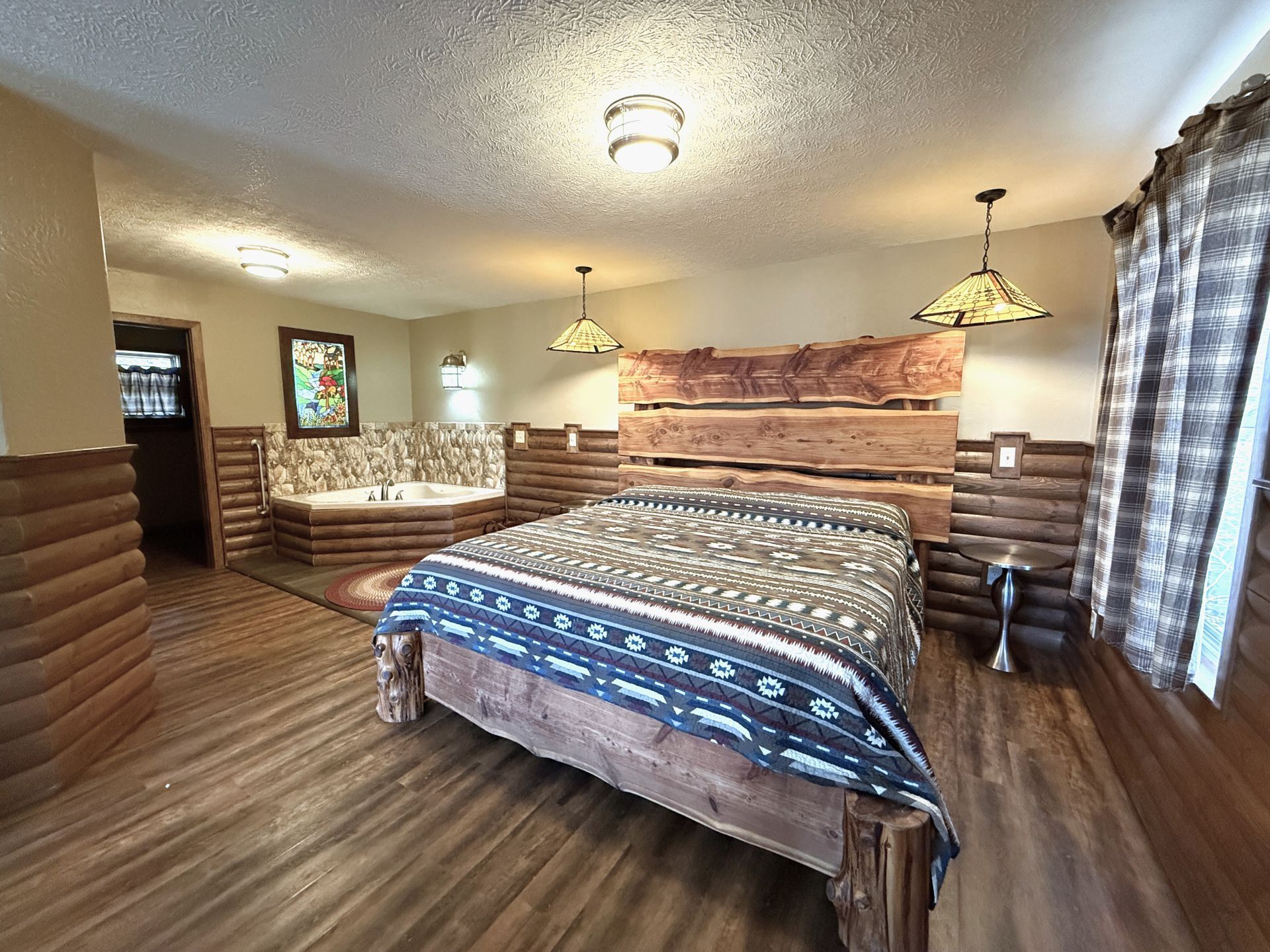 Spacious rustic bedroom with two beds, wood-paneled walls, and checkered curtains