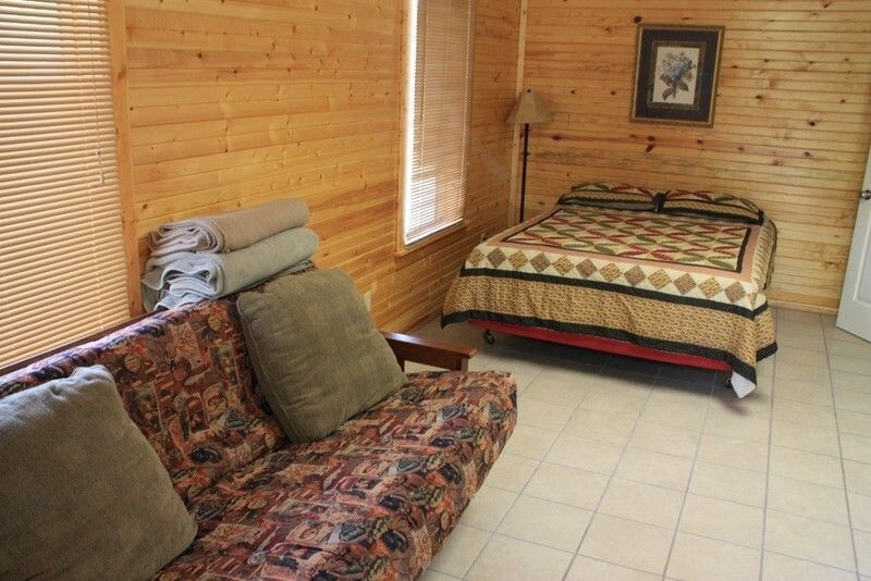Cozy wood-paneled bedroom with sofa, bed, and tiled floor