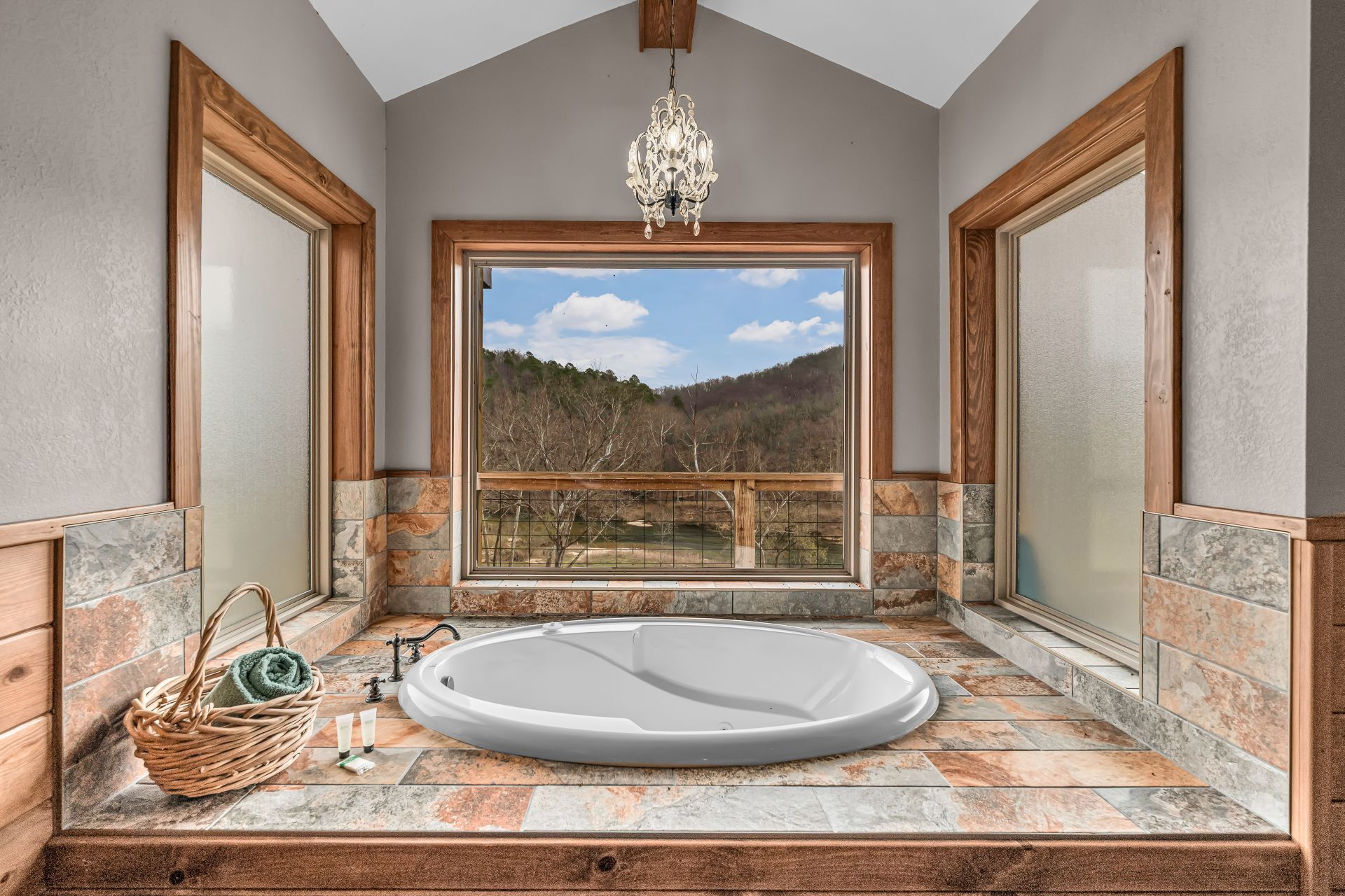 Elegant bathroom with a large window, corner soaking tub, and mountain view