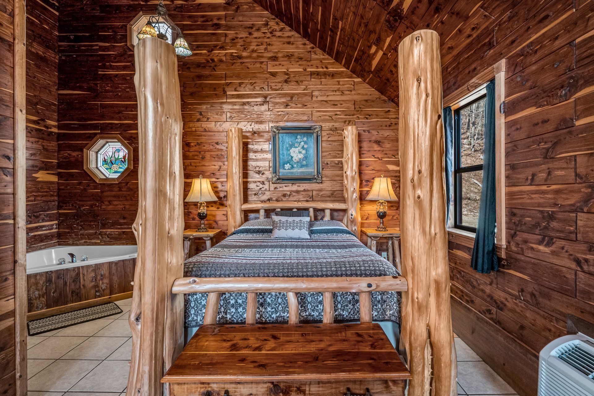 Rustic log cabin bedroom with a wooden four-poster bed, blue bedding, and warm lamp lighting