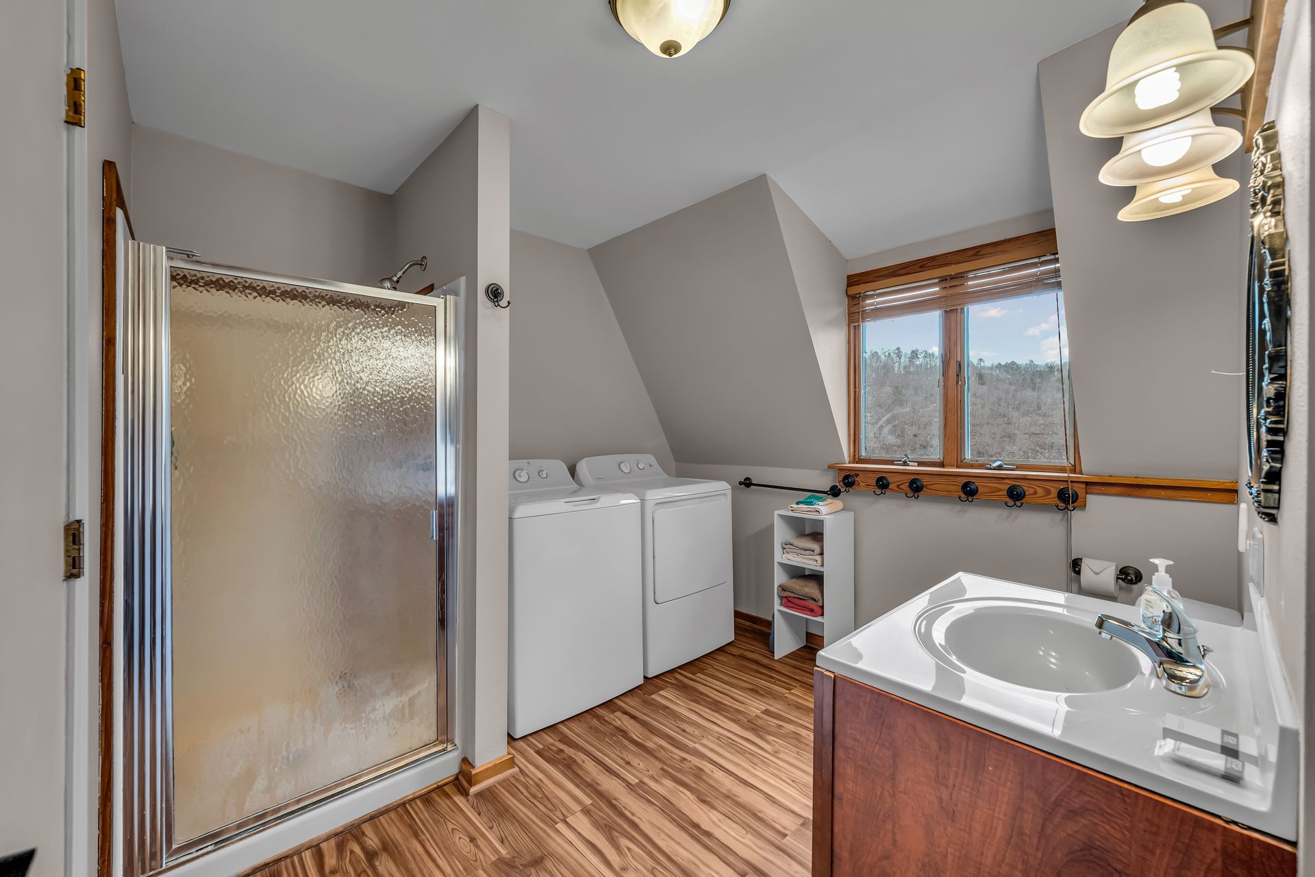 Bathroom with shower, washer and dryer, vanity sink, and window with wood trim