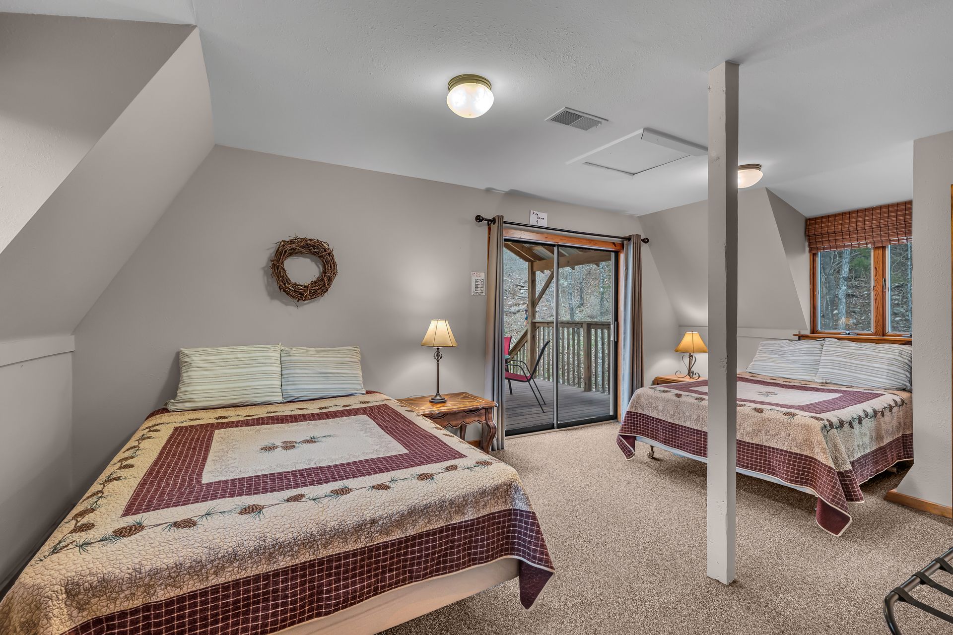 Spacious bedroom with two beds, a four-poster canopy bed, lamp, and sloped ceiling