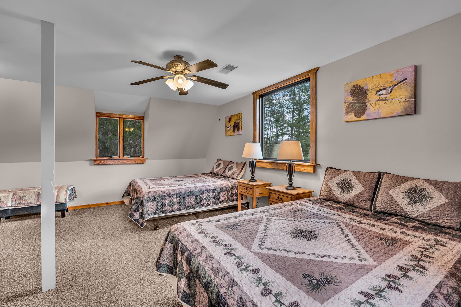 Bright bedroom with three beds, ceiling fan, carpet, and windows with wooden trim