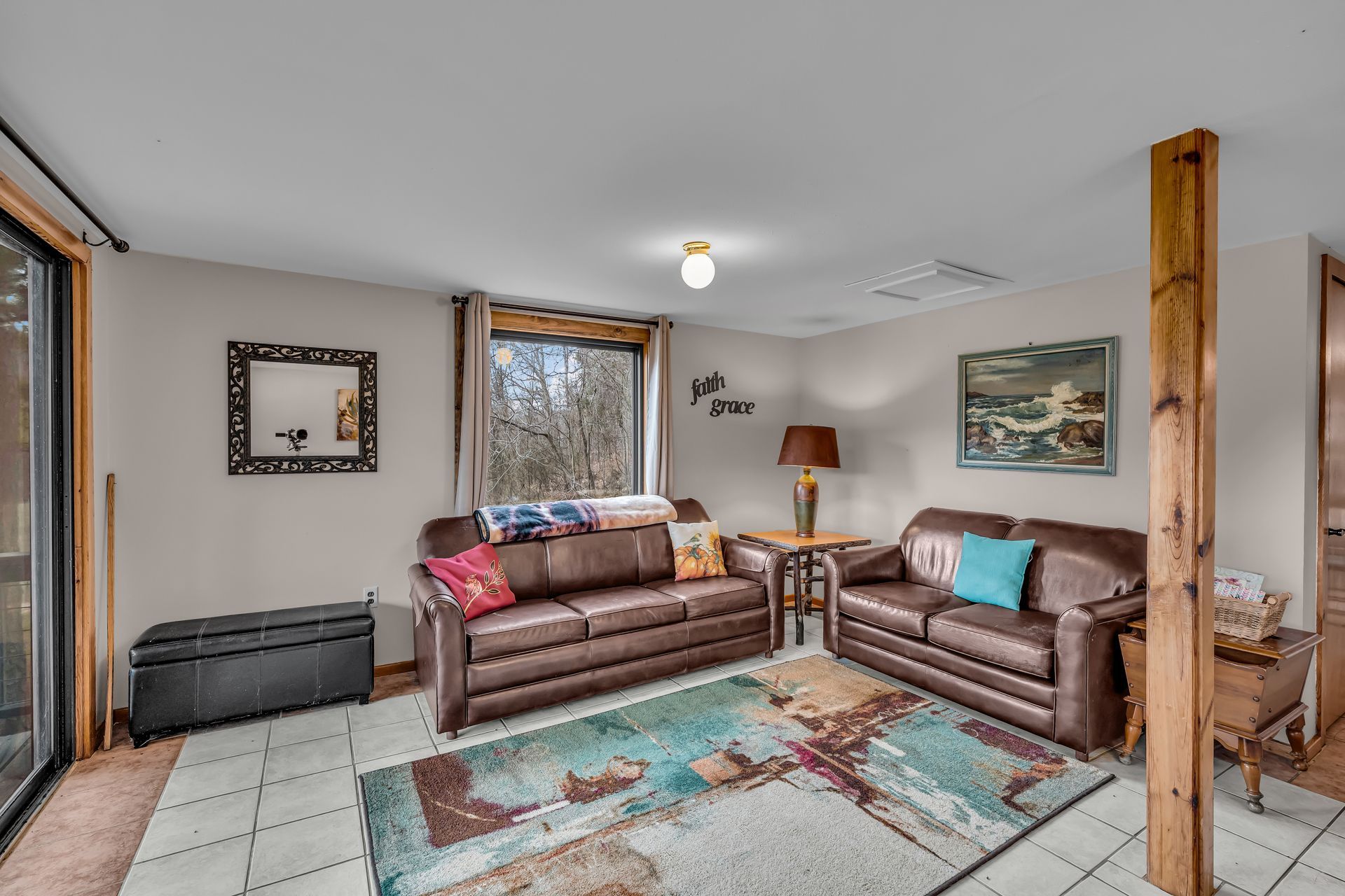 Living room with two brown sofas, colorful rug, floor lamp, wall art, and sliding glass door