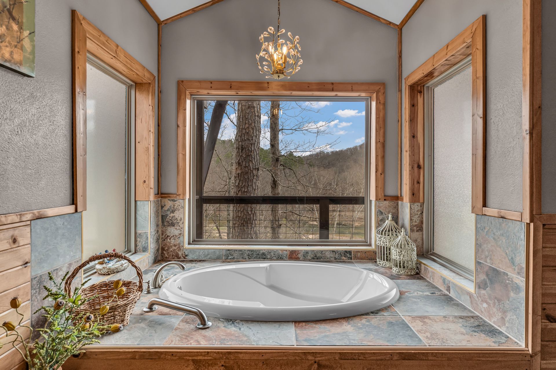 Bathroom vanity with a large round sink, stone countertop, and a window overlooking trees and mountains