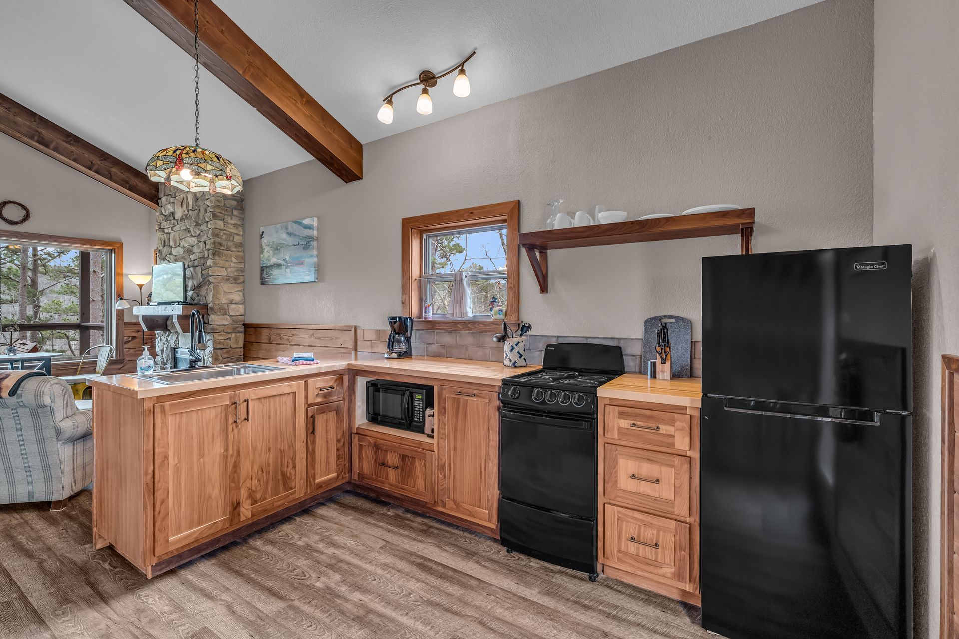 Kitchen with wood cabinets, black appliances, and a granite countertop in a bright open room
