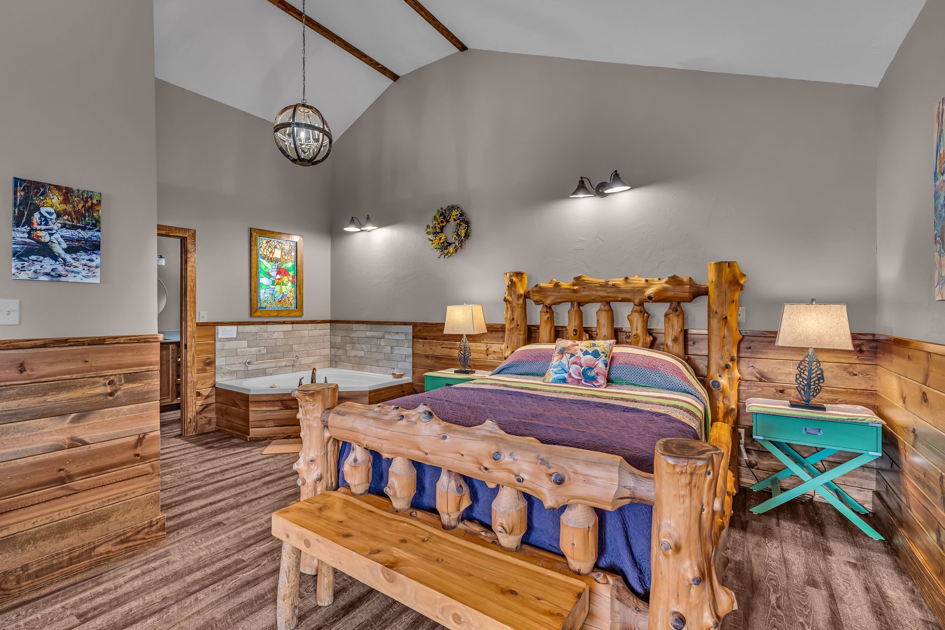 Rustic bedroom with a wooden bed, dresser, nightstands, and vaulted ceiling with hanging lights