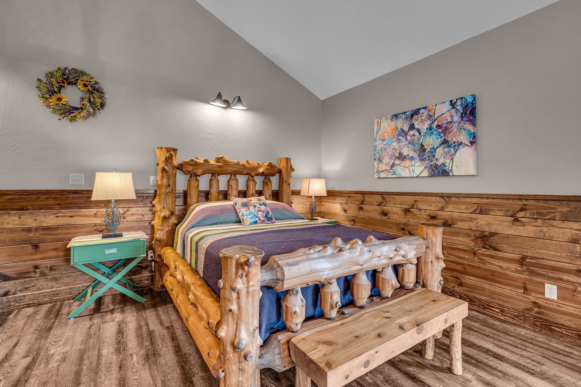Cozy rustic bedroom with log bed, turquoise side table, lamps, and colorful wall art