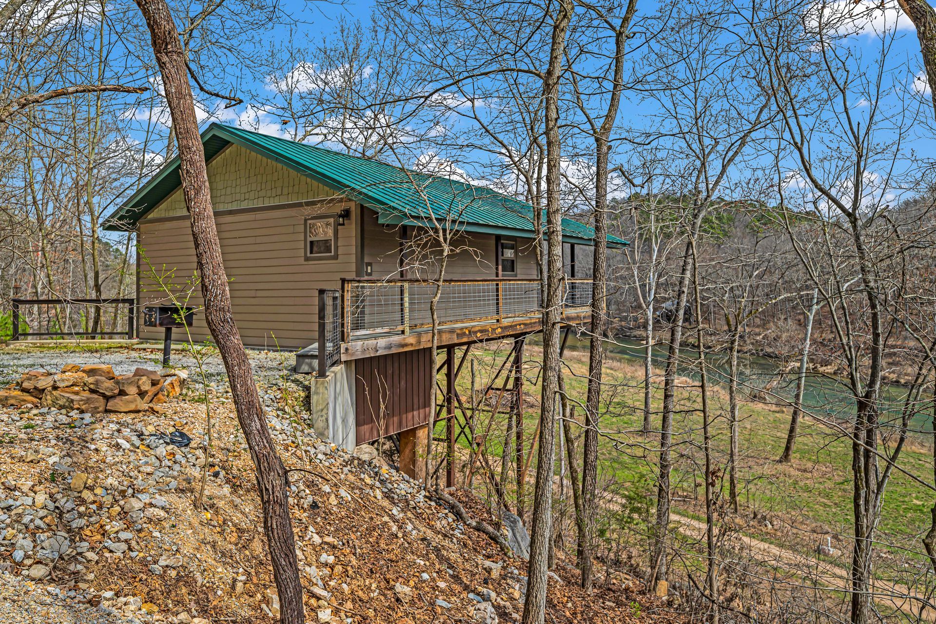 Cabin with green roof on a wooded hillside overlooking a valley in autumn