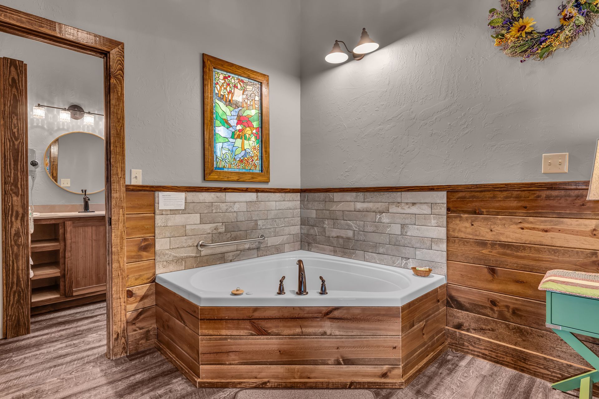 Bathroom with corner soaking tub, wood-paneled walls, tile wainscoting, and stained-glass window