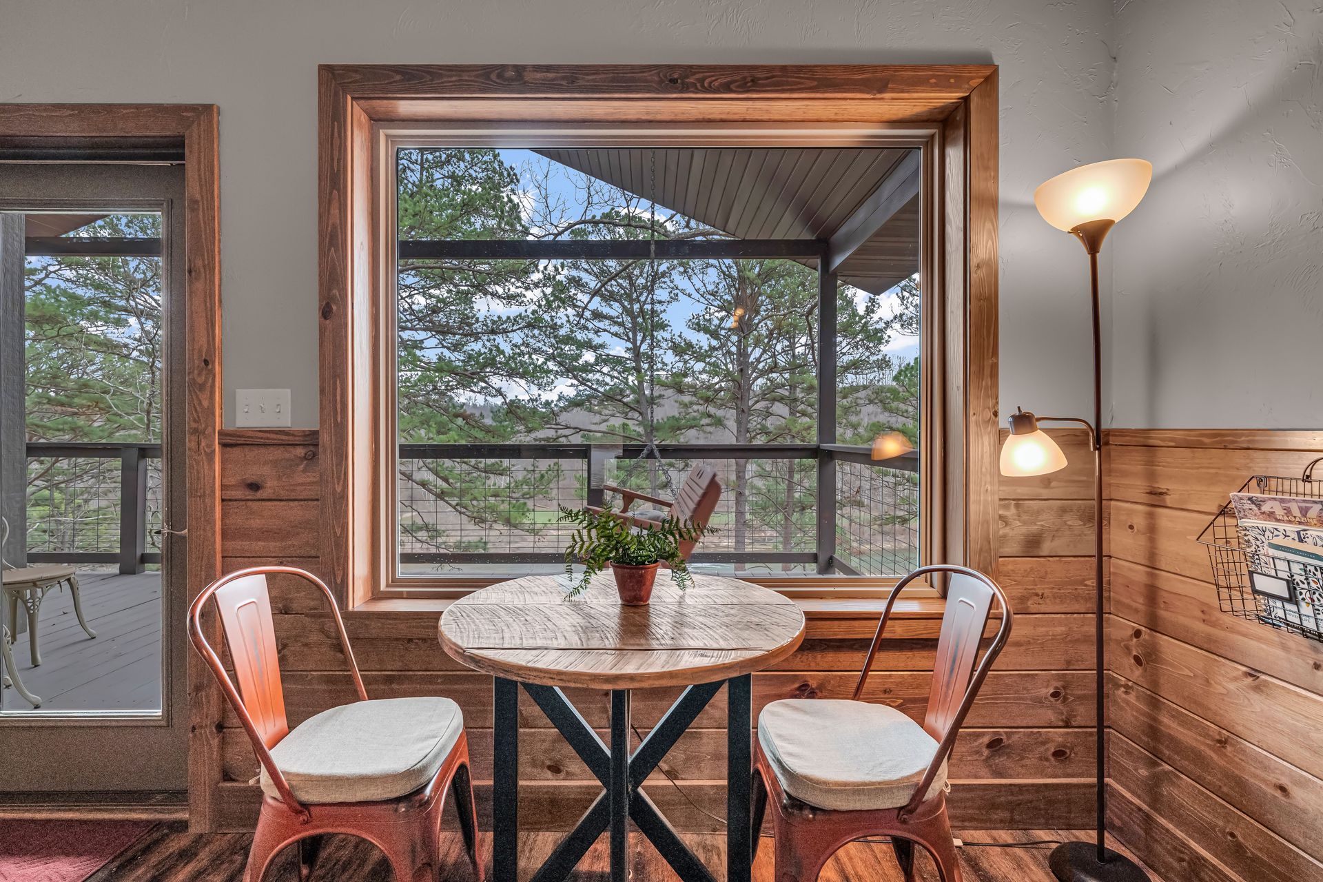 Small dining nook with round table, two chairs, large window, and floor lamp in a cozy room