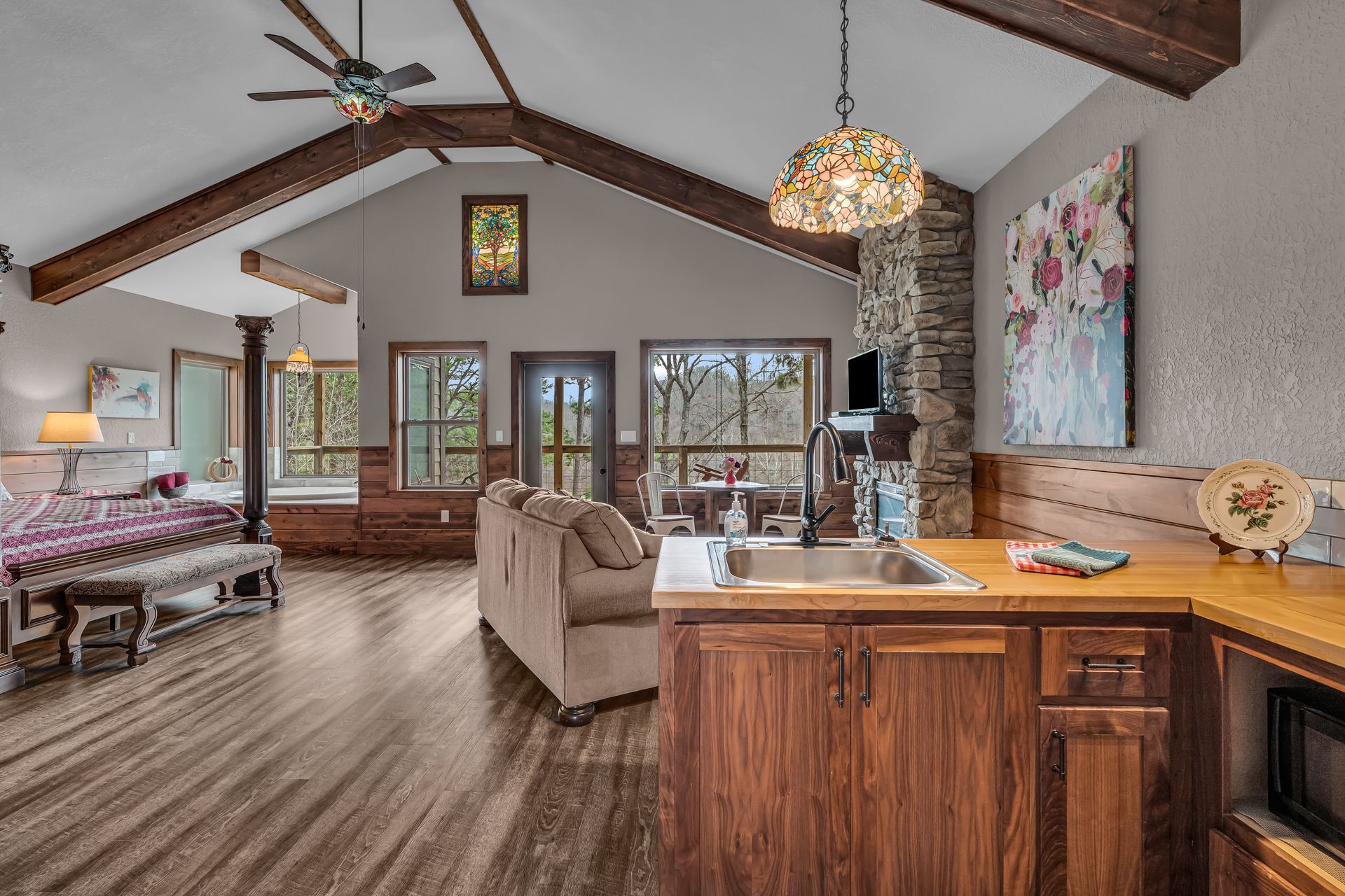 Open-concept living room with vaulted wood ceiling, fireplace, beige sofa, and kitchen island