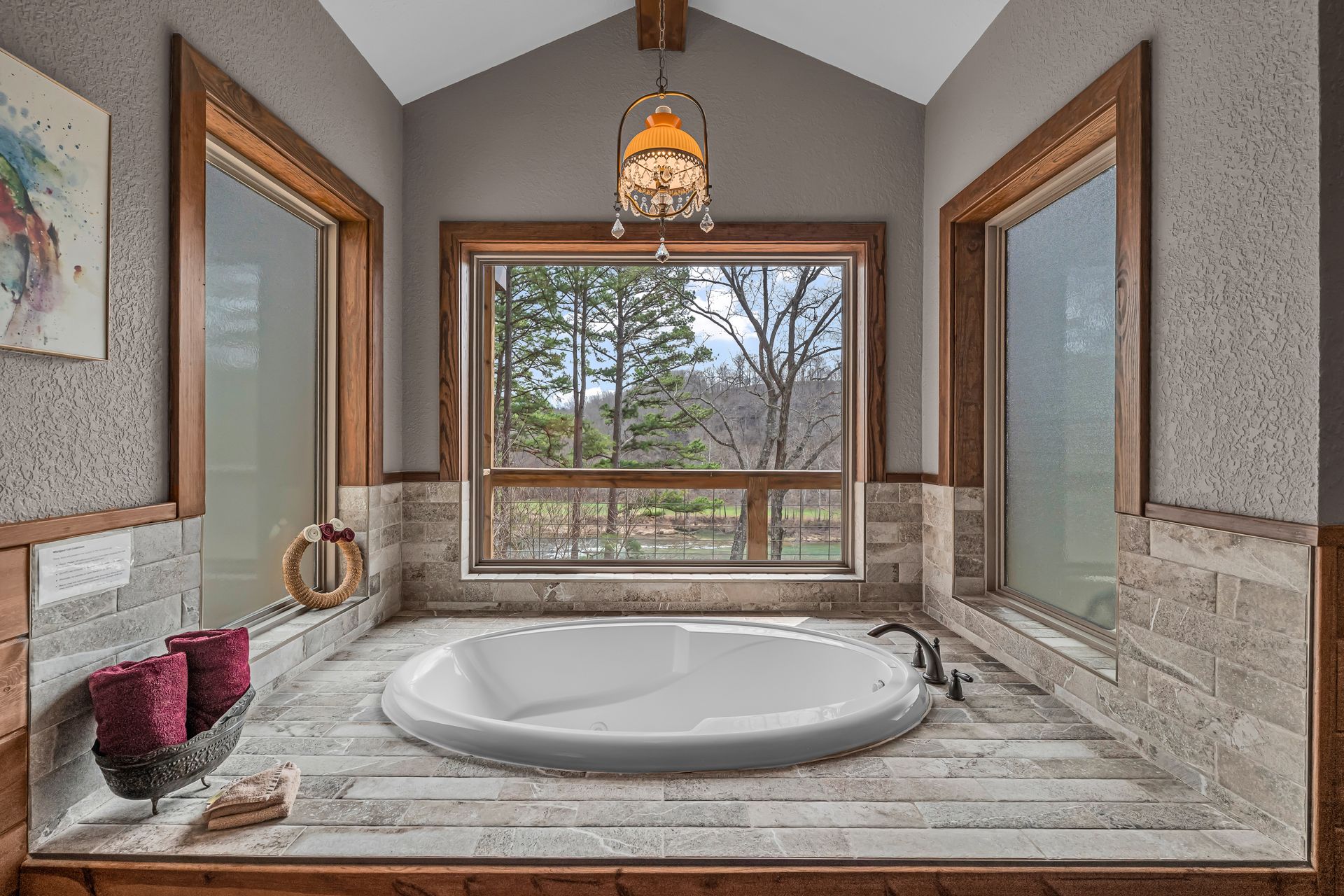 Luxurious bathroom with a marble soaking tub, large window, and wood-trimmed gray walls