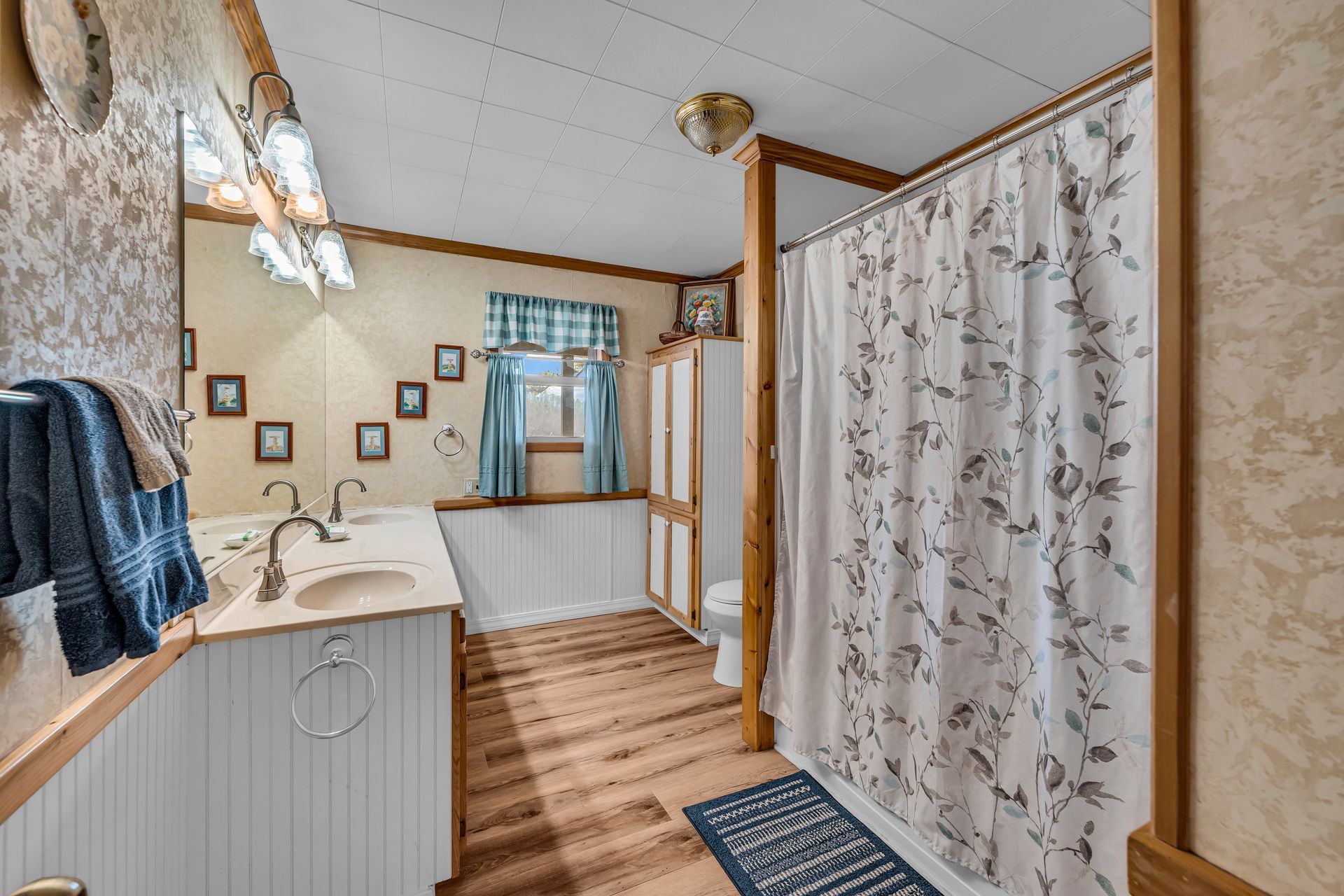 Bathroom with a shower curtain, vanity sink, mirror, and wood floor accents