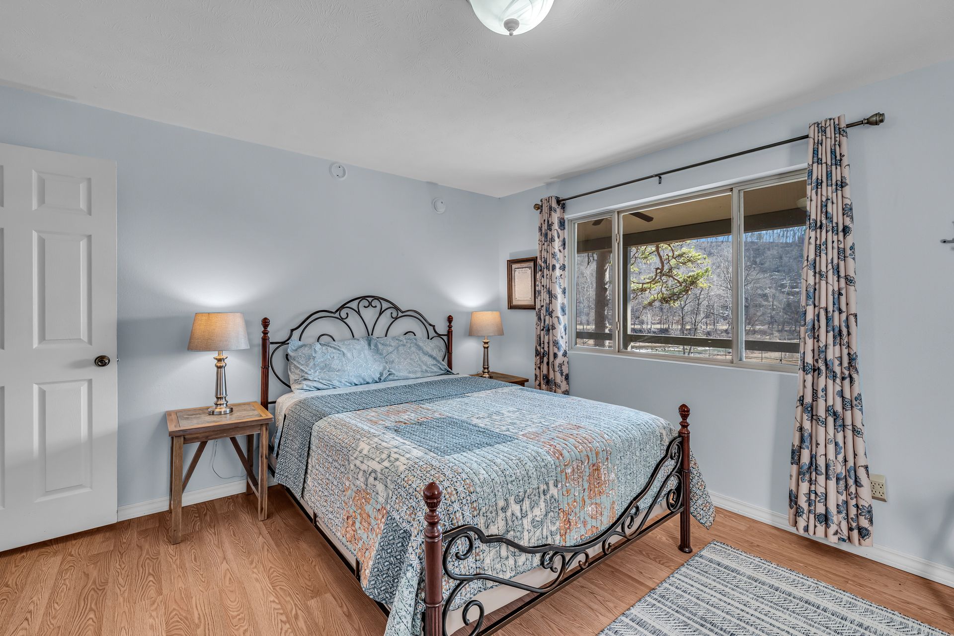 Bedroom with wrought-iron bed, bedside lamps, window, and patterned curtains