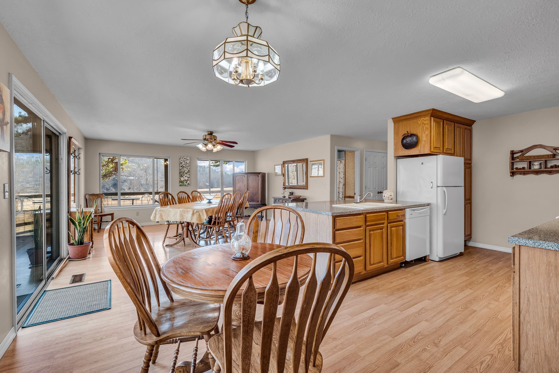 Bright dining area and kitchen with wooden table, chairs, white appliances, and light wood floors