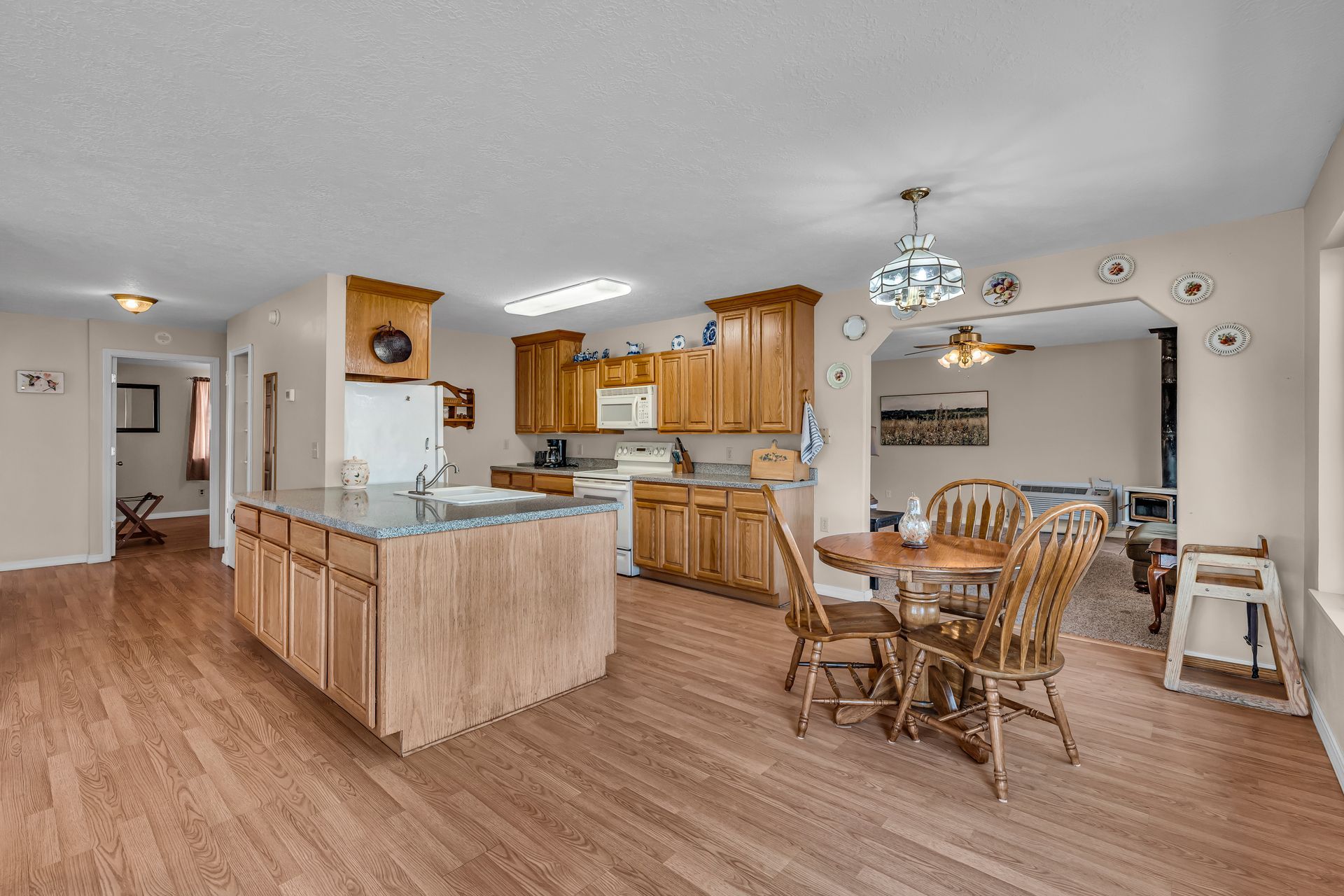 Open-concept kitchen and dining area with light wood cabinets, island, table, and ceiling fan.