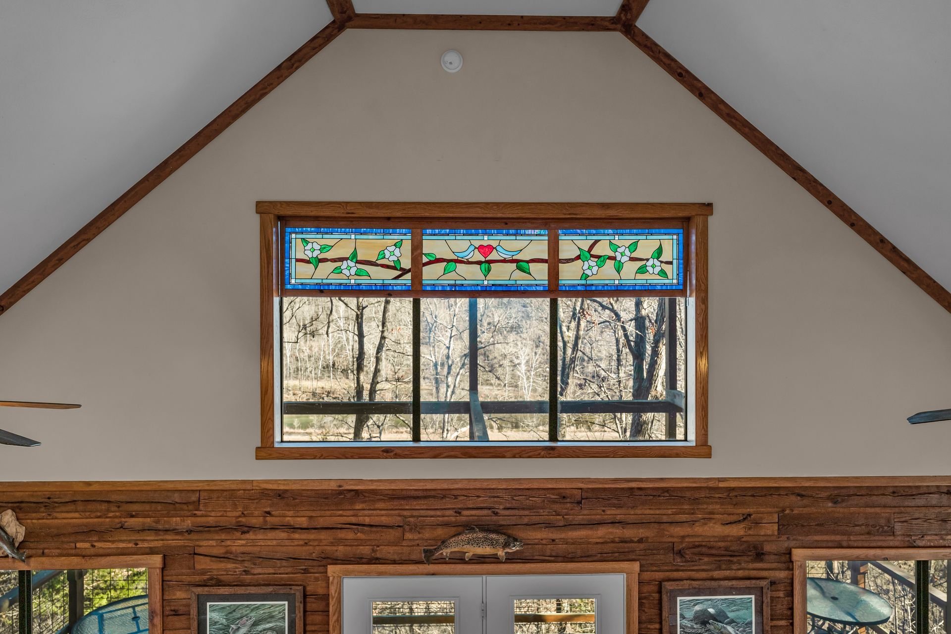 Wood-paneled room with a centered stained-glass window and exposed ceiling beams