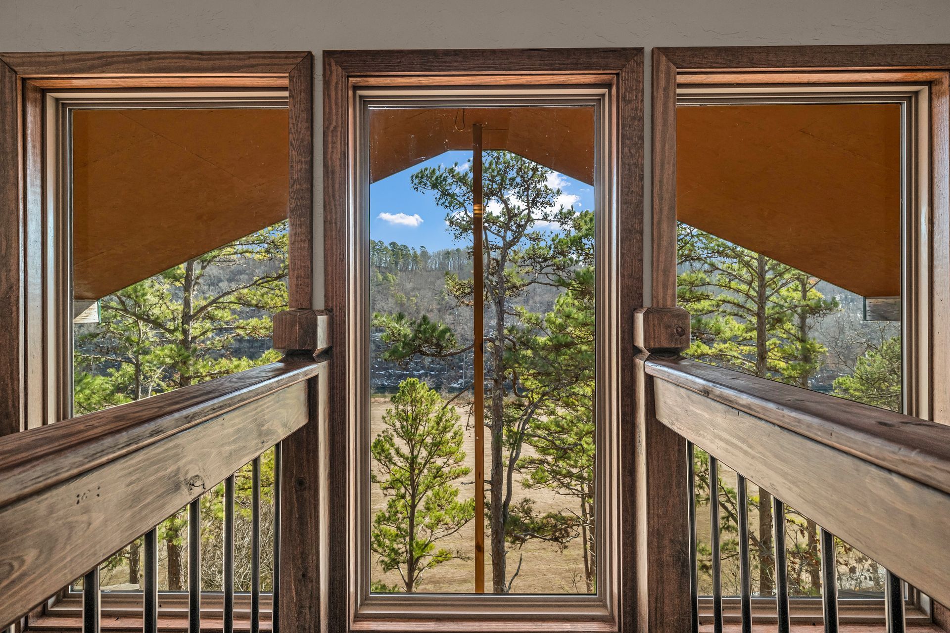 Wooden balcony with mountain and pine forest view through a central glass door