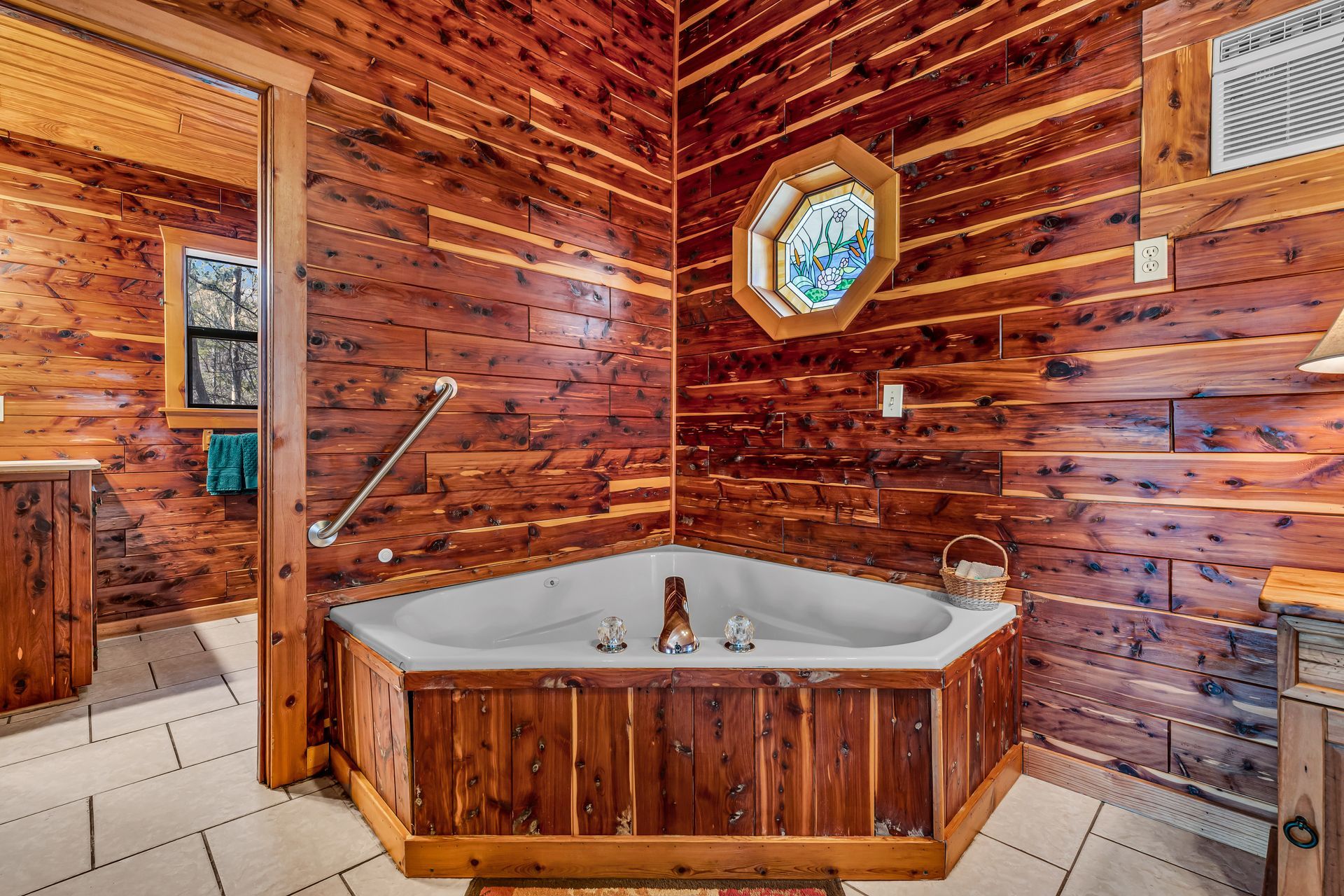 Rustic wood-paneled bathroom with a corner soaking tub and octagonal window