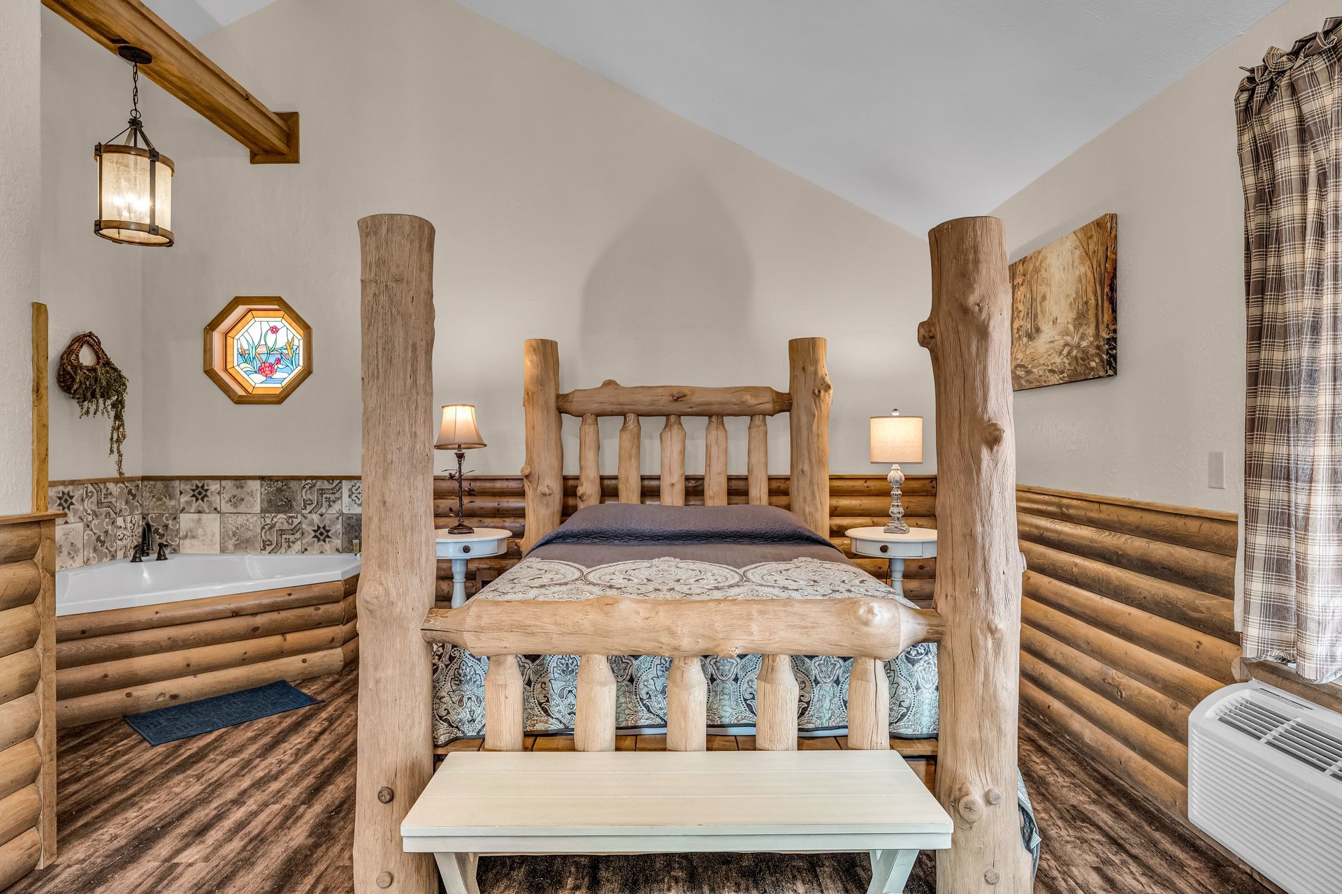 Rustic log cabin bedroom with a wooden bed, lamps, and patterned quilt