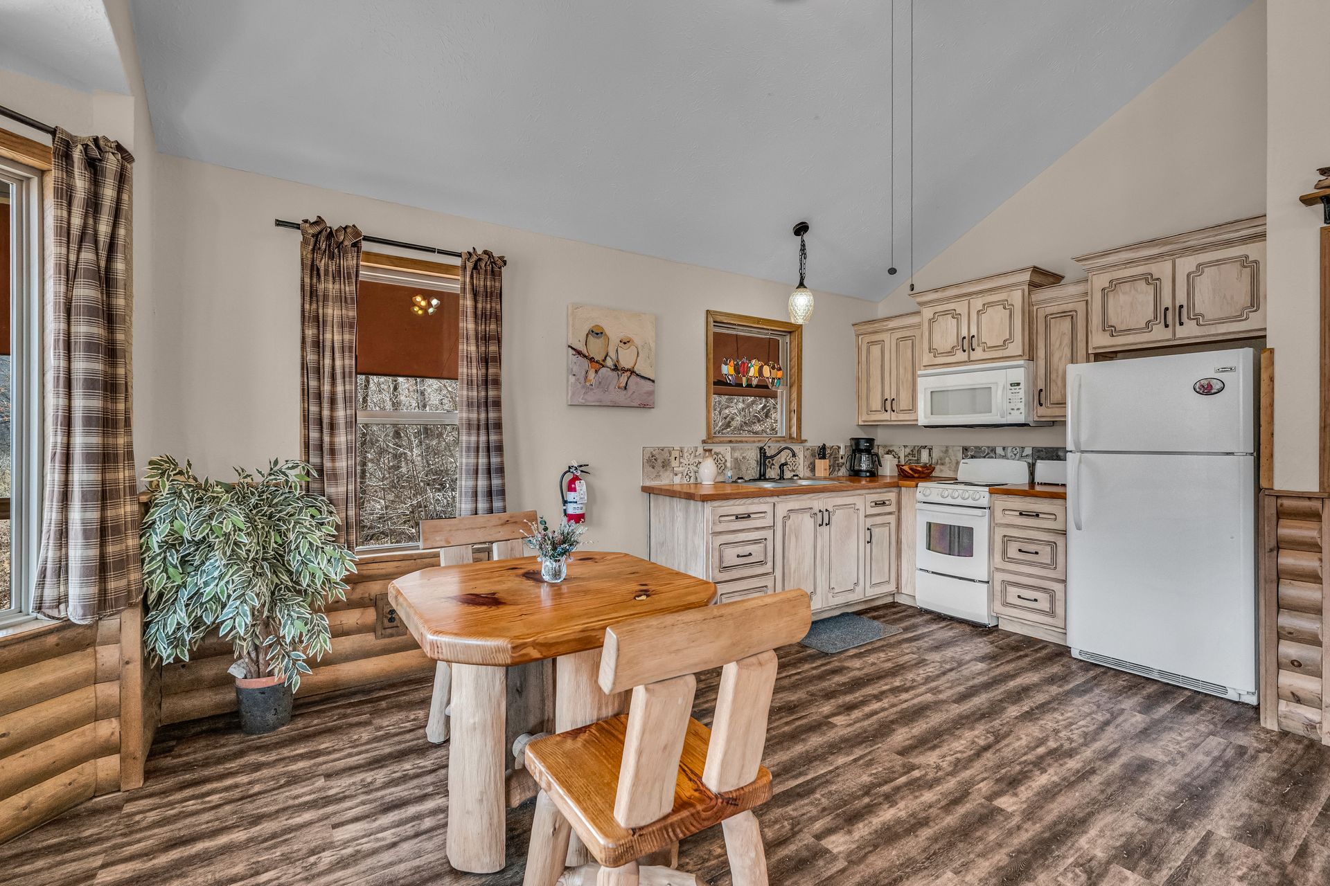 Cozy kitchen with wood cabinets, white appliances, striped floor, and a small dining table by windows