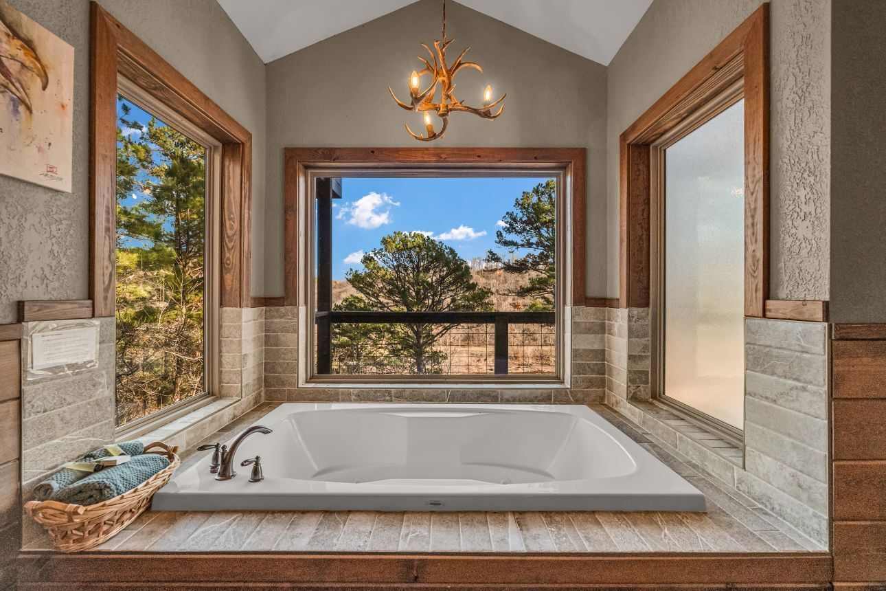 Luxury bathroom with a soaking tub and large windows overlooking trees and blue sky