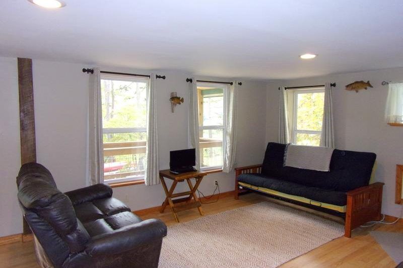 Bright living room with leather recliner, black sofa, small TV stand, and large windows
