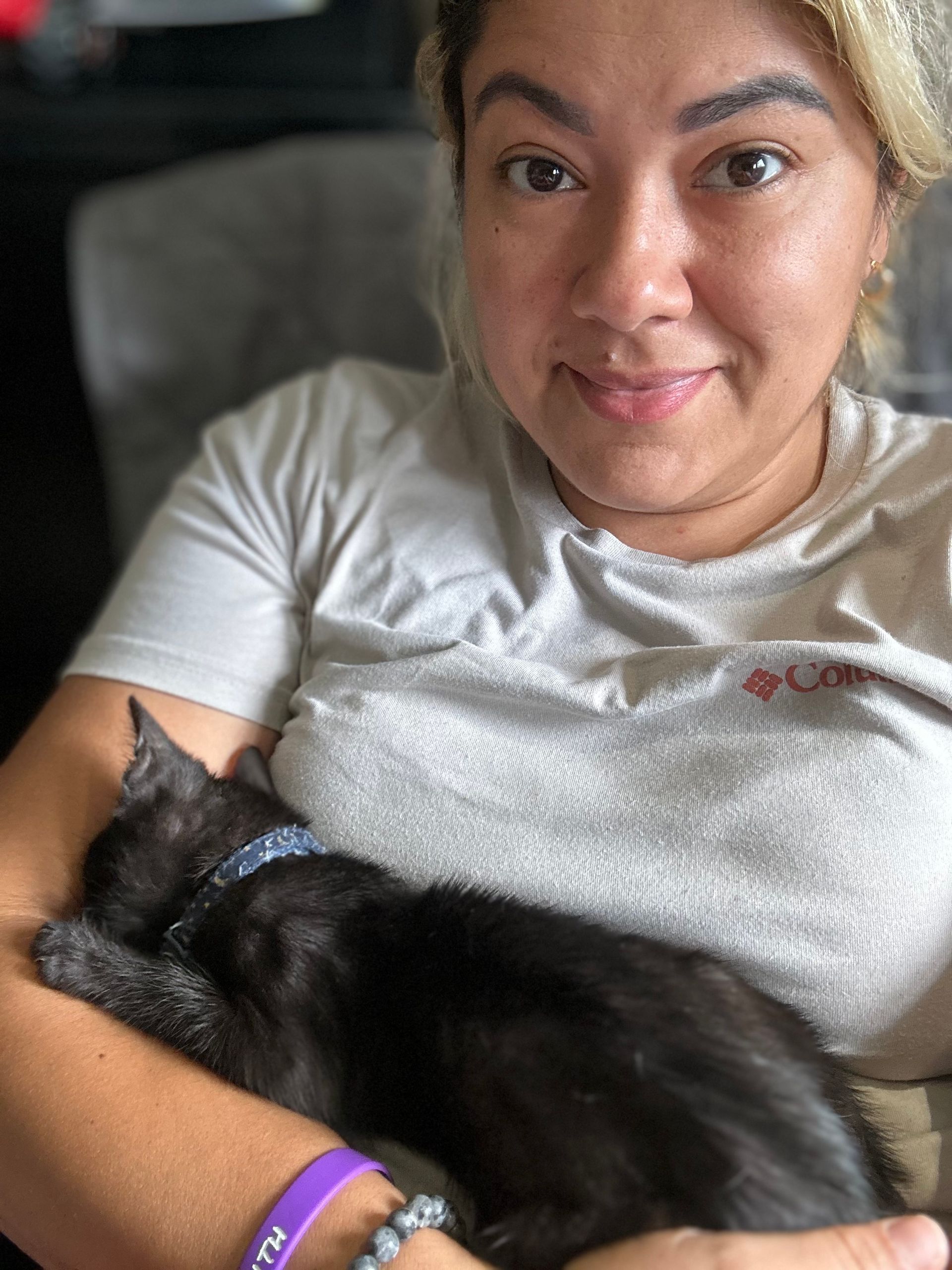 A woman in a white shirt is holding a black cat
