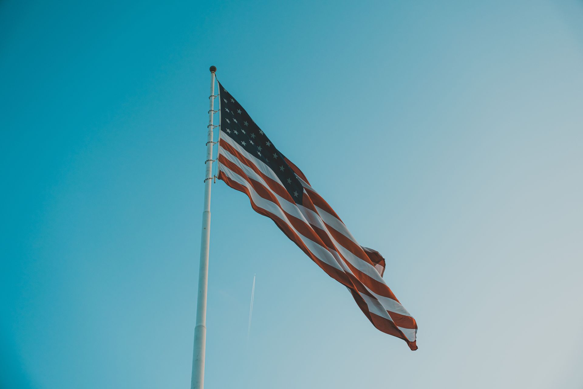 American flag waving on a flagpole against a clear blue sky