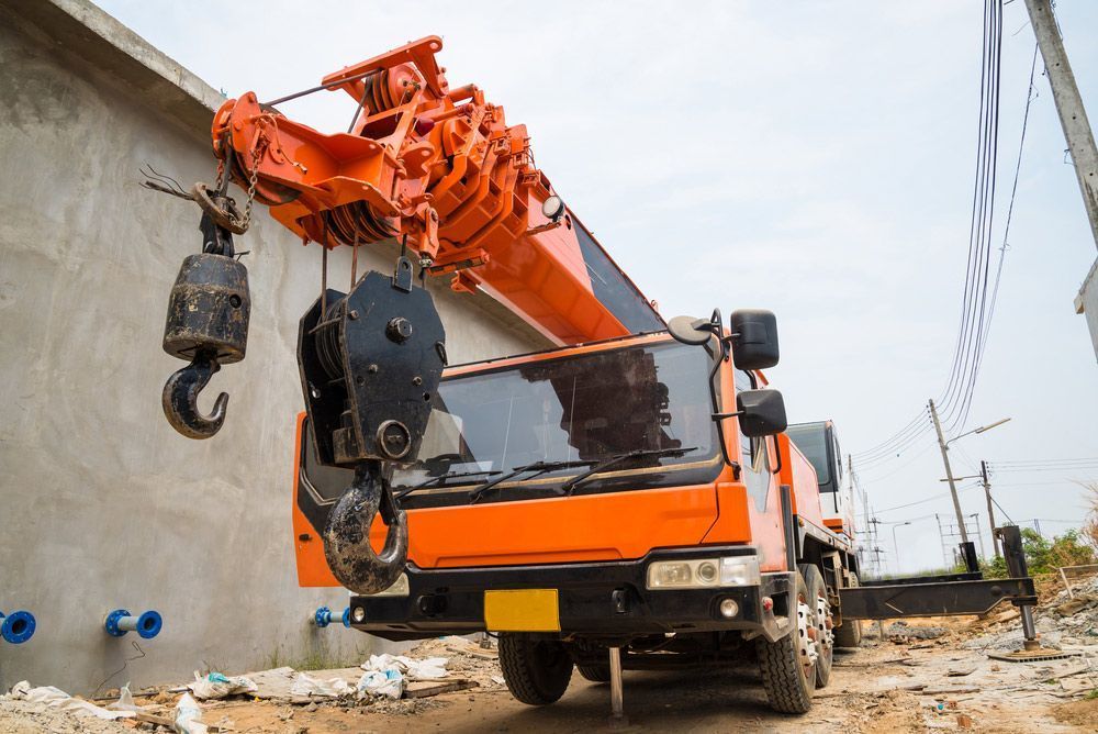 Orange Crane Truck Lifting Near a Concrete Wall; Daylight — Statewide Lift & Shift Pty Ltd In Paget, QLD