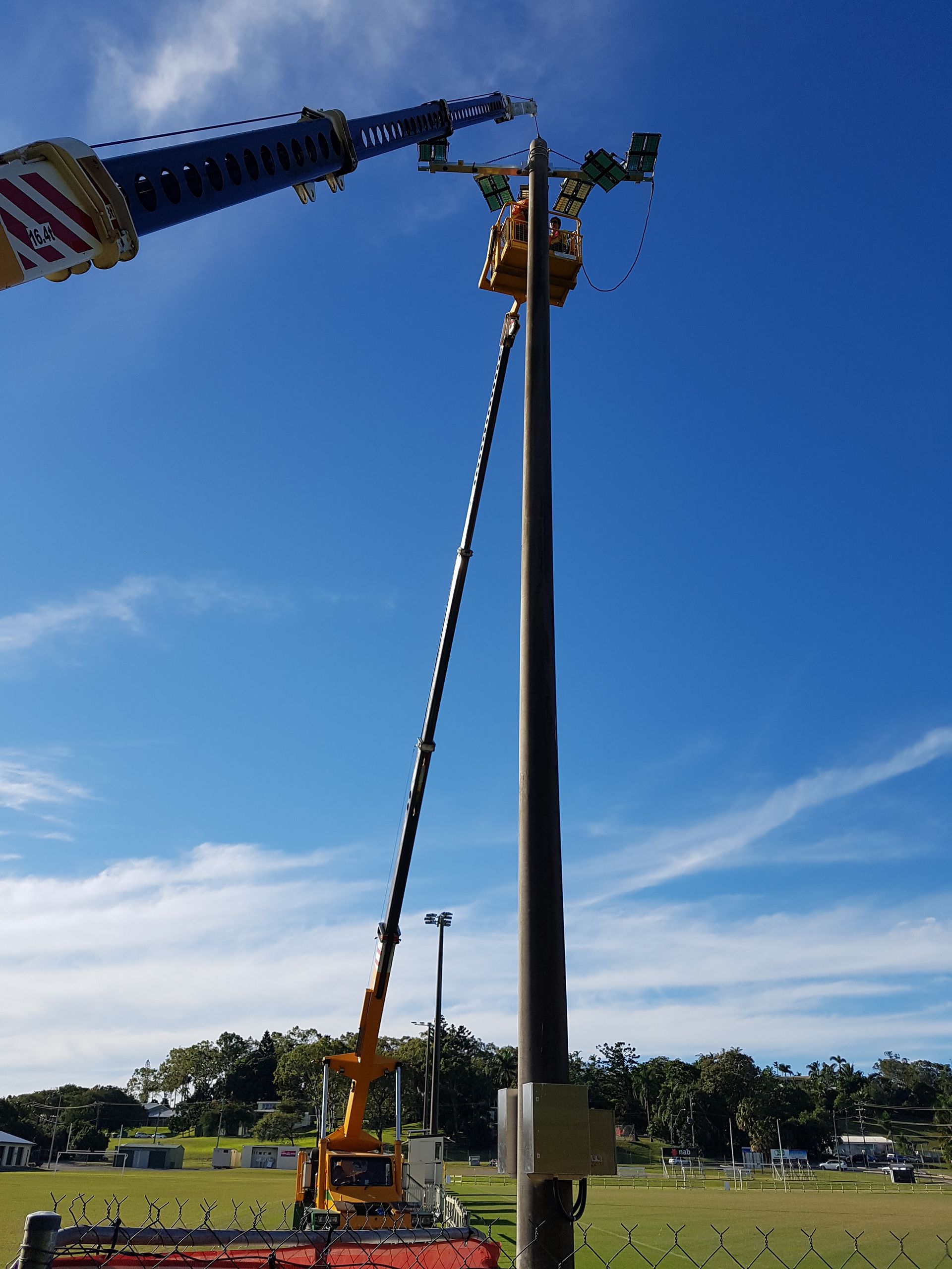 A Crane Lifts Sports Field Floodlights Onto a Tall Pole Against a Blue Sky — Statewide Lift & Shift Pty Ltd In Paget, QLD