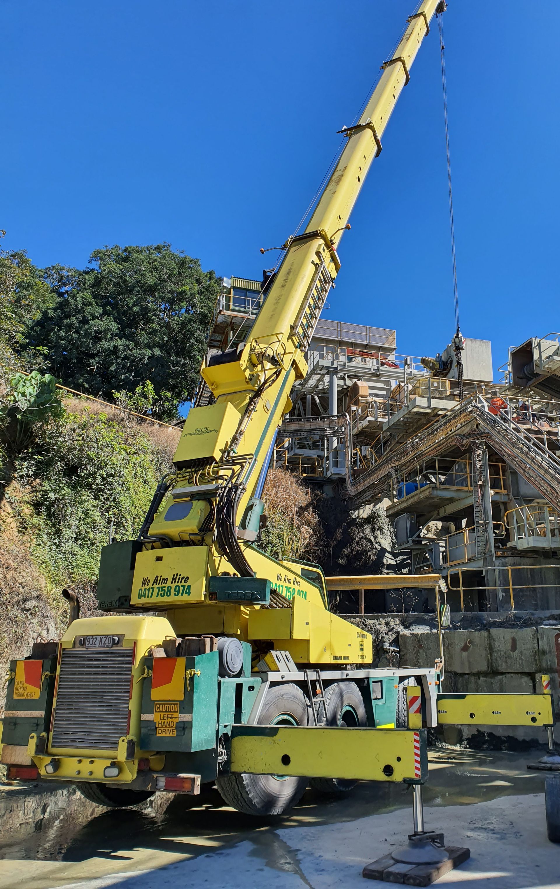 Yellow crane at a construction site, against a hillside and blue sky — Statewide Lift & Shift Pty Ltd In Paget, QLD