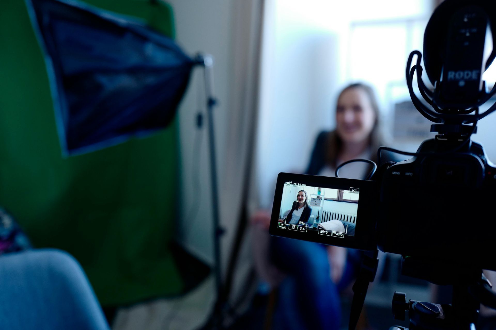 A woman is sitting in front of a camera being filmed.