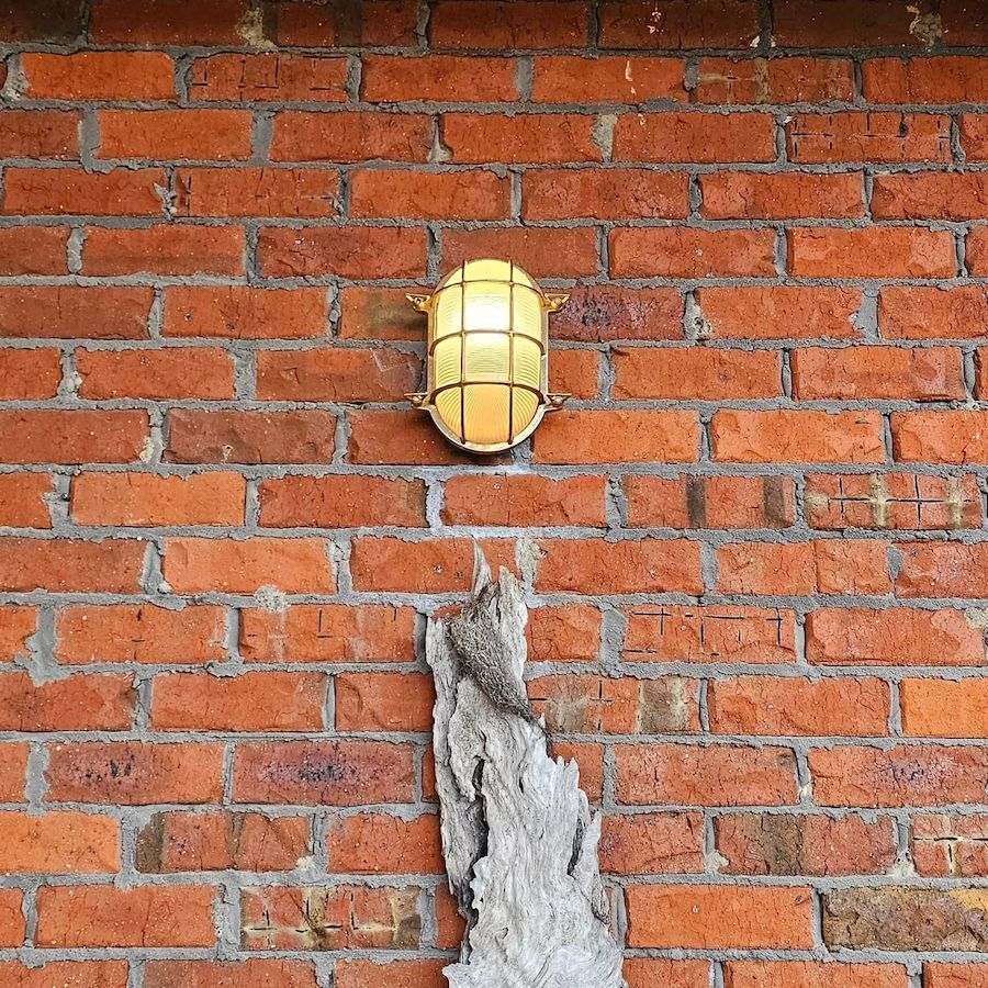 Brick Wall With a Glowing Light Fixture and a Piece of Gray Wood — White Rose Electrical in Coffs Harbour, NSW