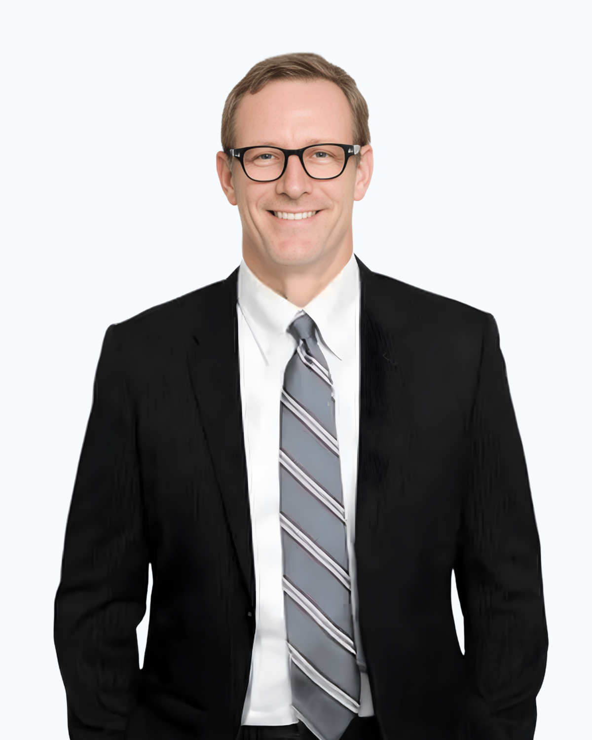 A man in a suit and black shirt is standing with his hands in his pockets.