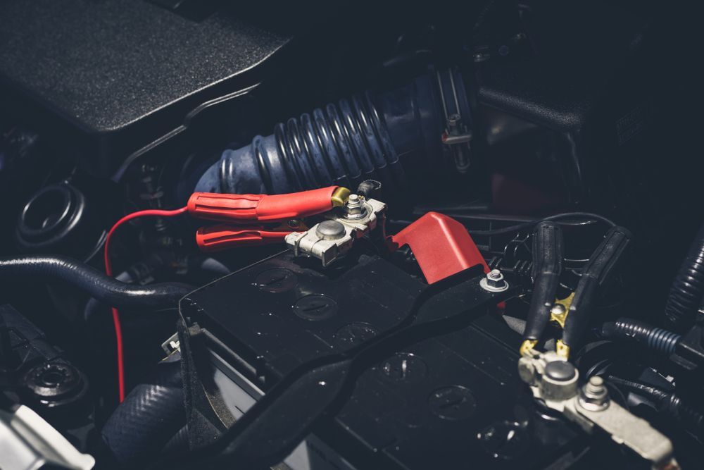 Car Battery With Red Jumper Cables — Symbiote Systems in Airlie Beach, QLD