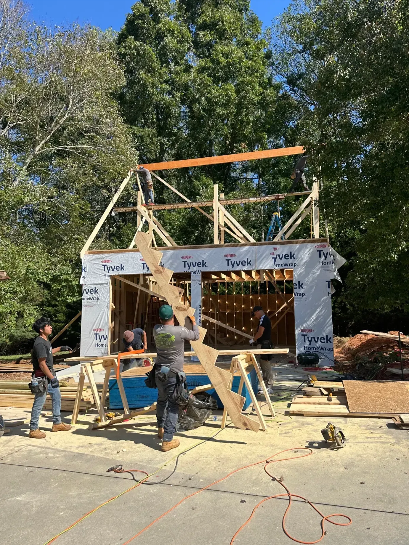 Construction of a two-story wooden addition to a brick house. Ladder and lumber present.