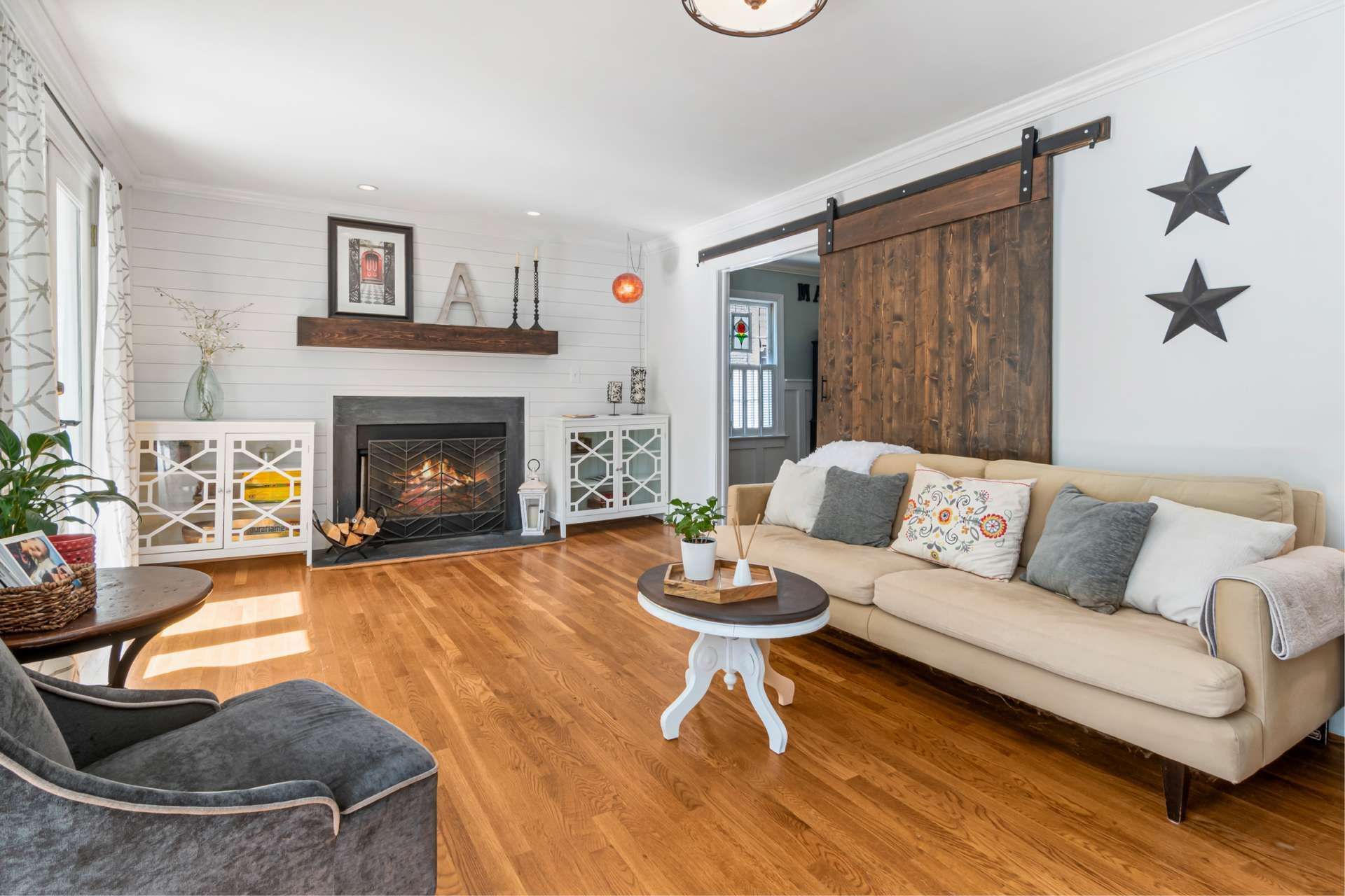 Living room with fireplace, wood floors, beige sofa, and a wooden sliding door.