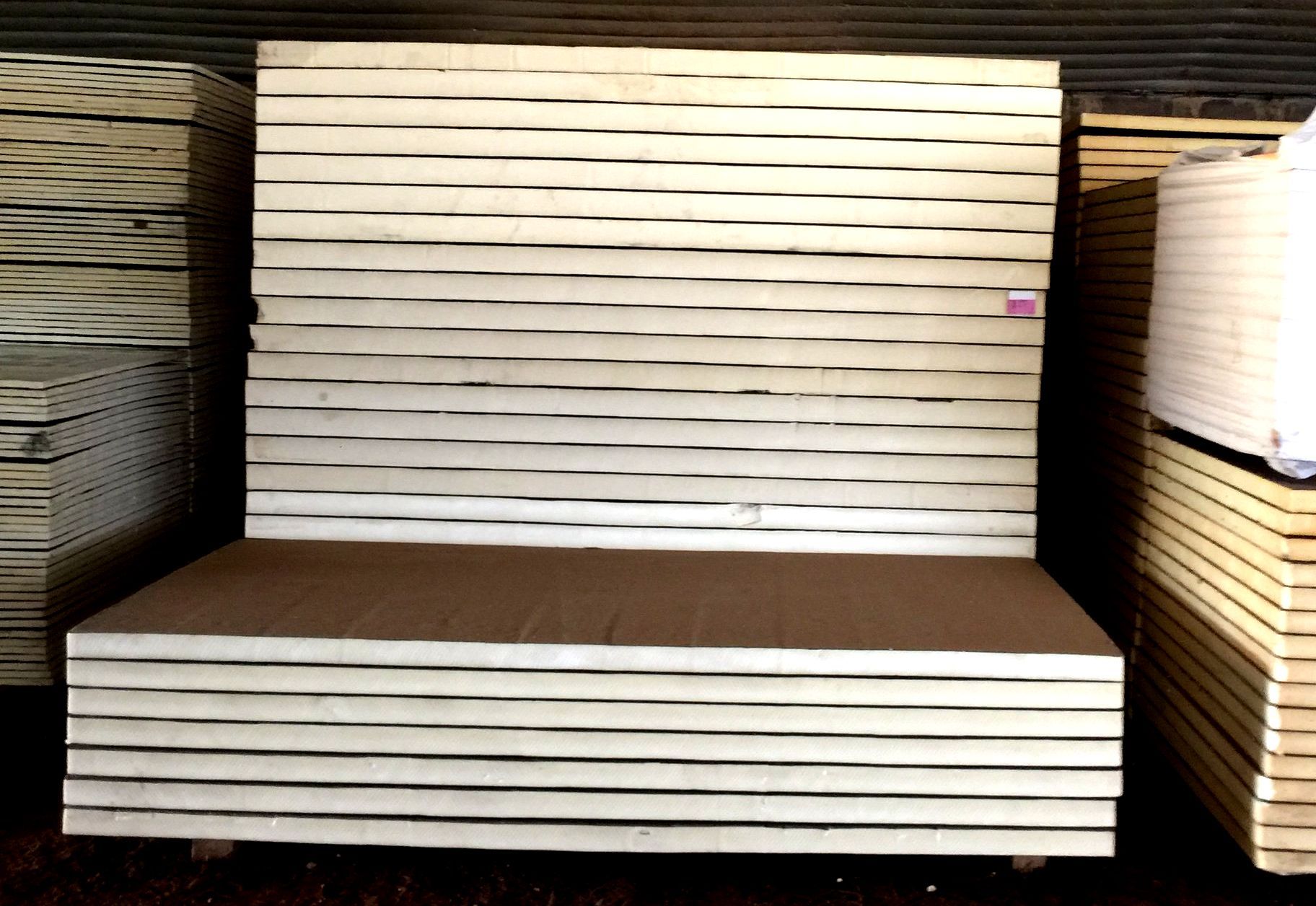 Stacked sheets of light-colored plywood in a warehouse setting.