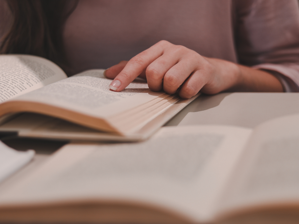Una mujer está sentada en una mesa leyendo un libro.